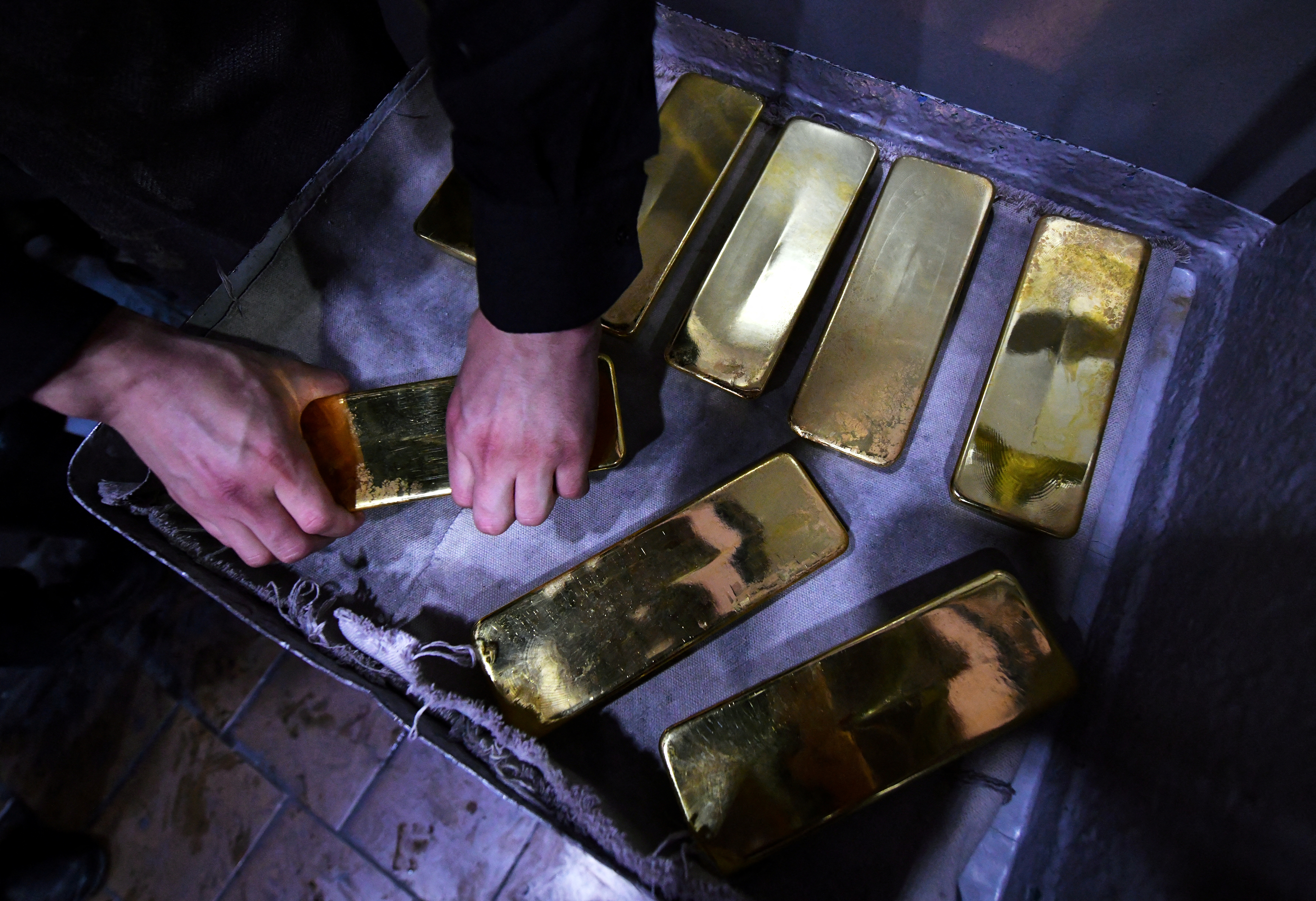 An employee processes ingots of 99.99 percent pure gold at the Krastsvetmet non-ferrous metals plant in Krasnoyarsk