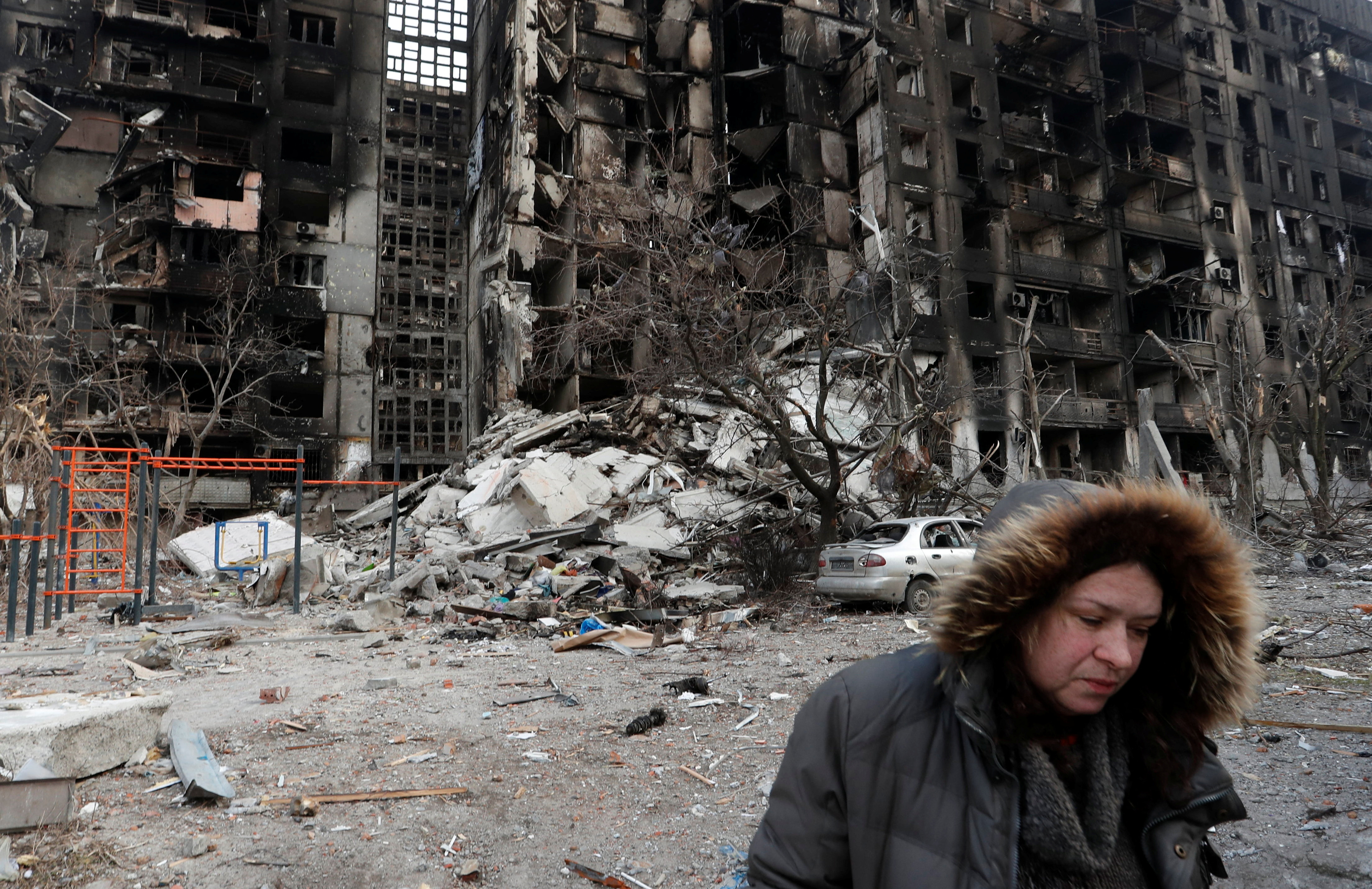 Nurse Svetlana Savchenko stands next to the destroyed building where her apartment was located in Mariupol
