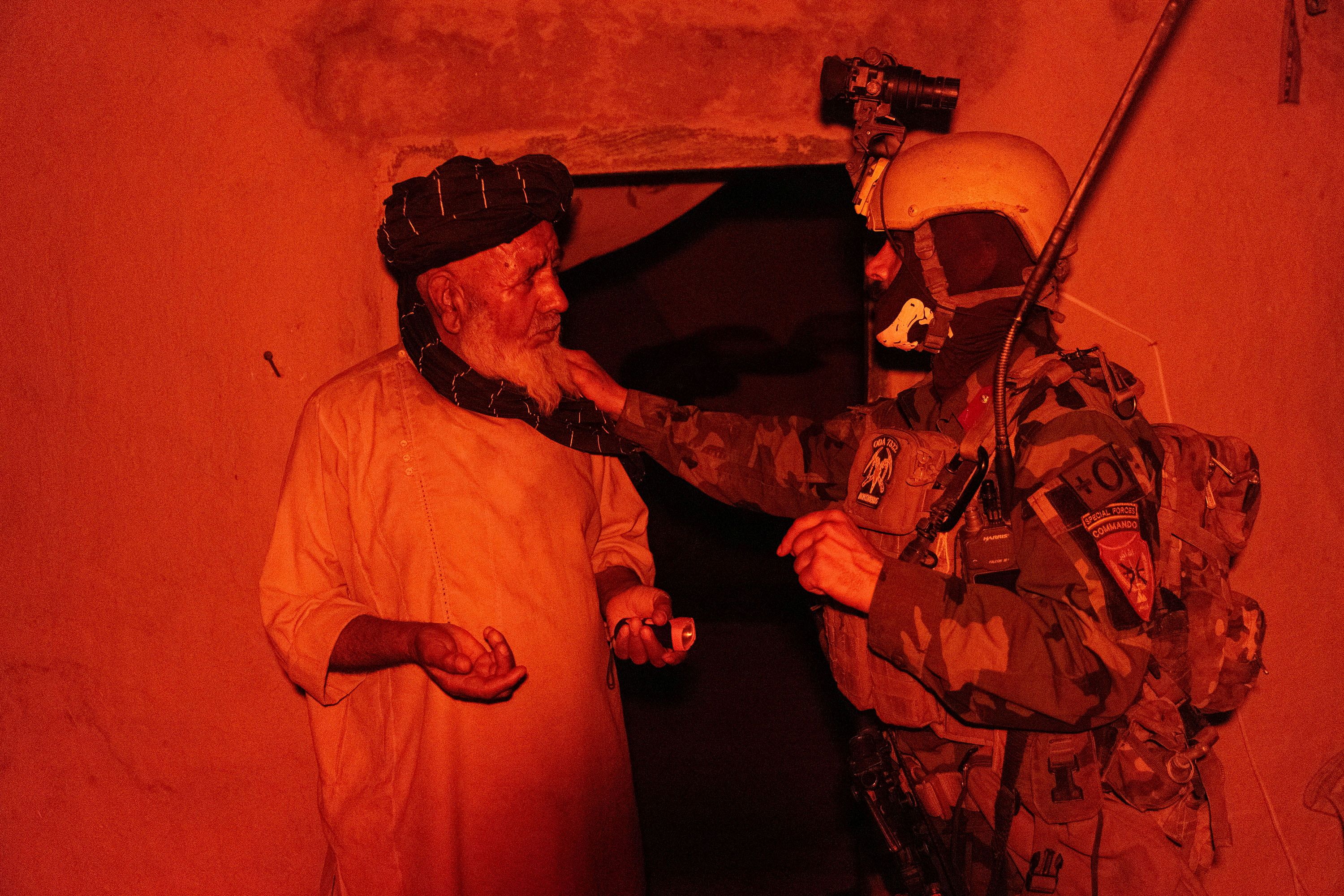 A member of the Afghan Special Forces speaks to a resident as others search his house during a mission against Taliban, in Kandahar province
