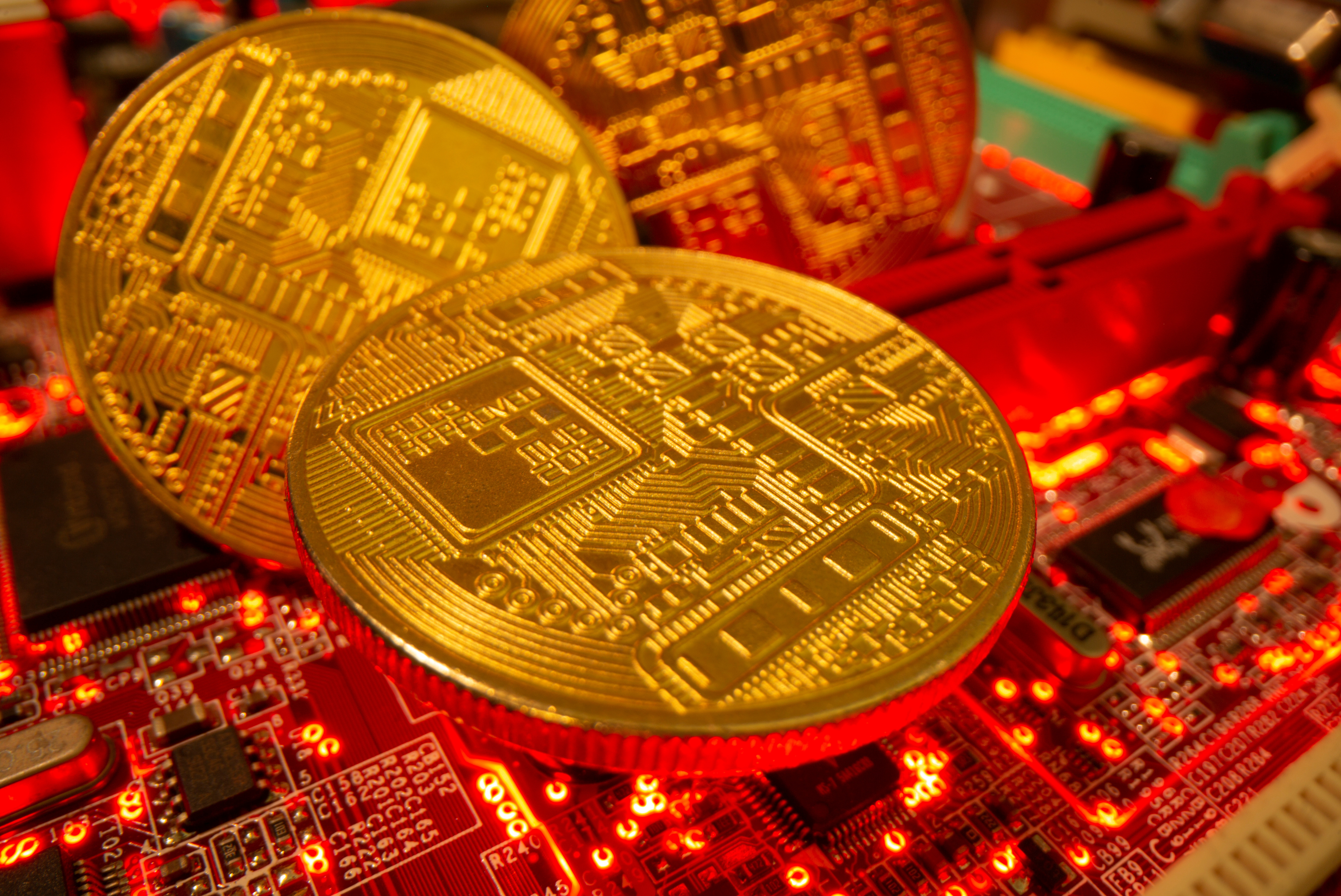 Representations of the virtual currency stand on a motherboard in this picture illustration