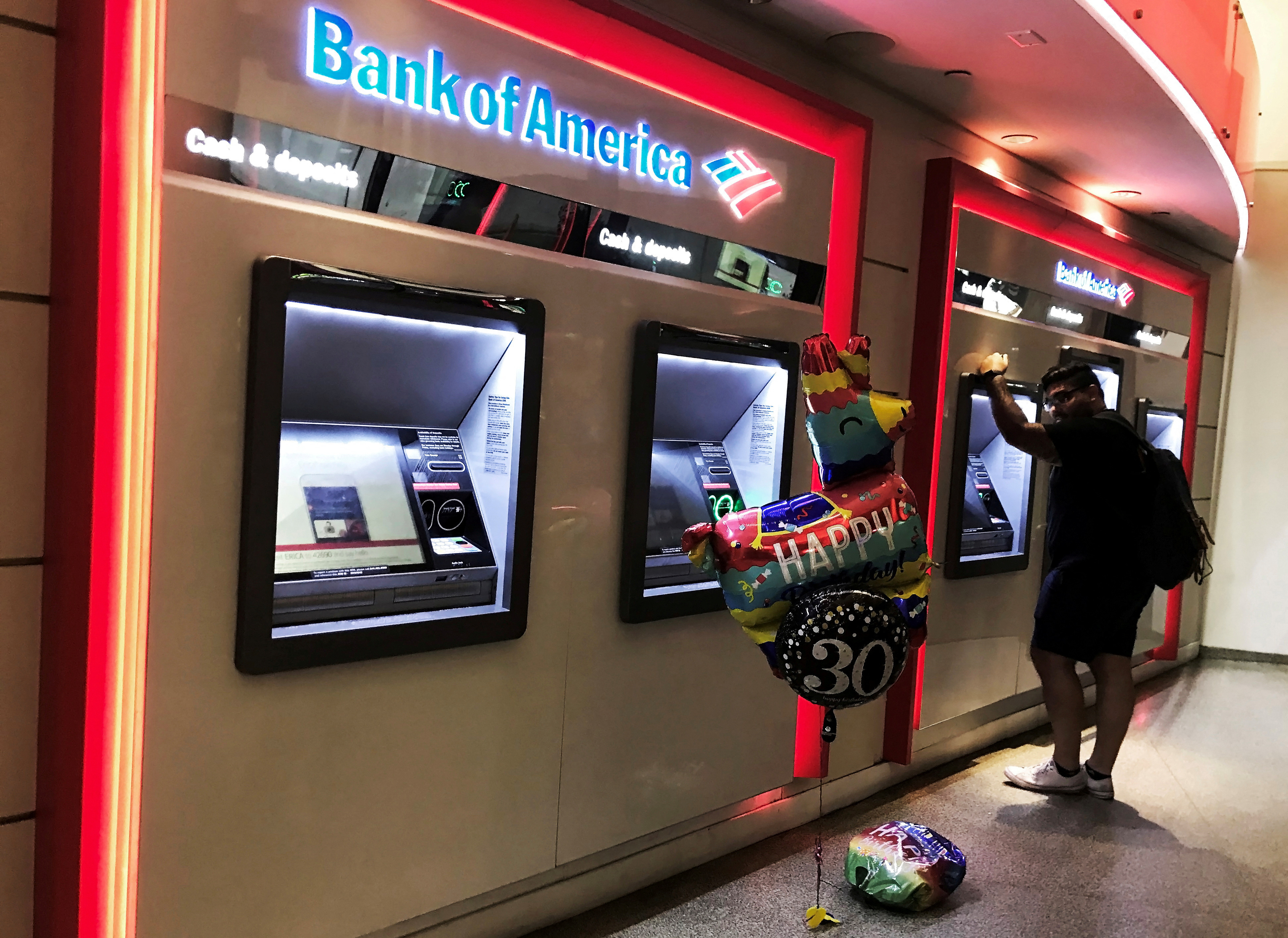 A man uses an ATM machine next an inflatable plastic balloon inside a Bank of America branch in Times Square in New York