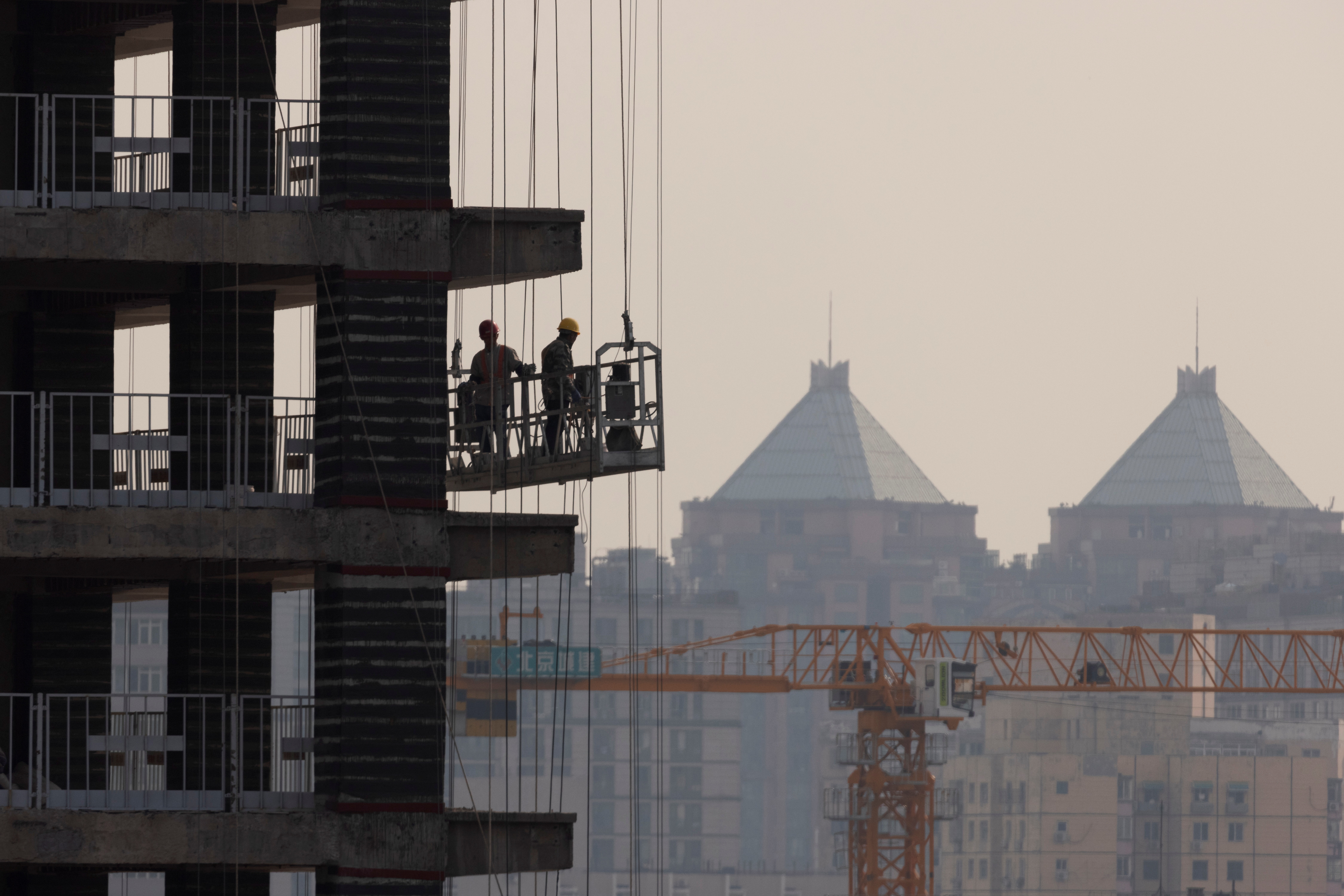 Men work at the construction site of a highrise building in Beijing, China, October 18, 2021.   REUTERS/Thomas Peter