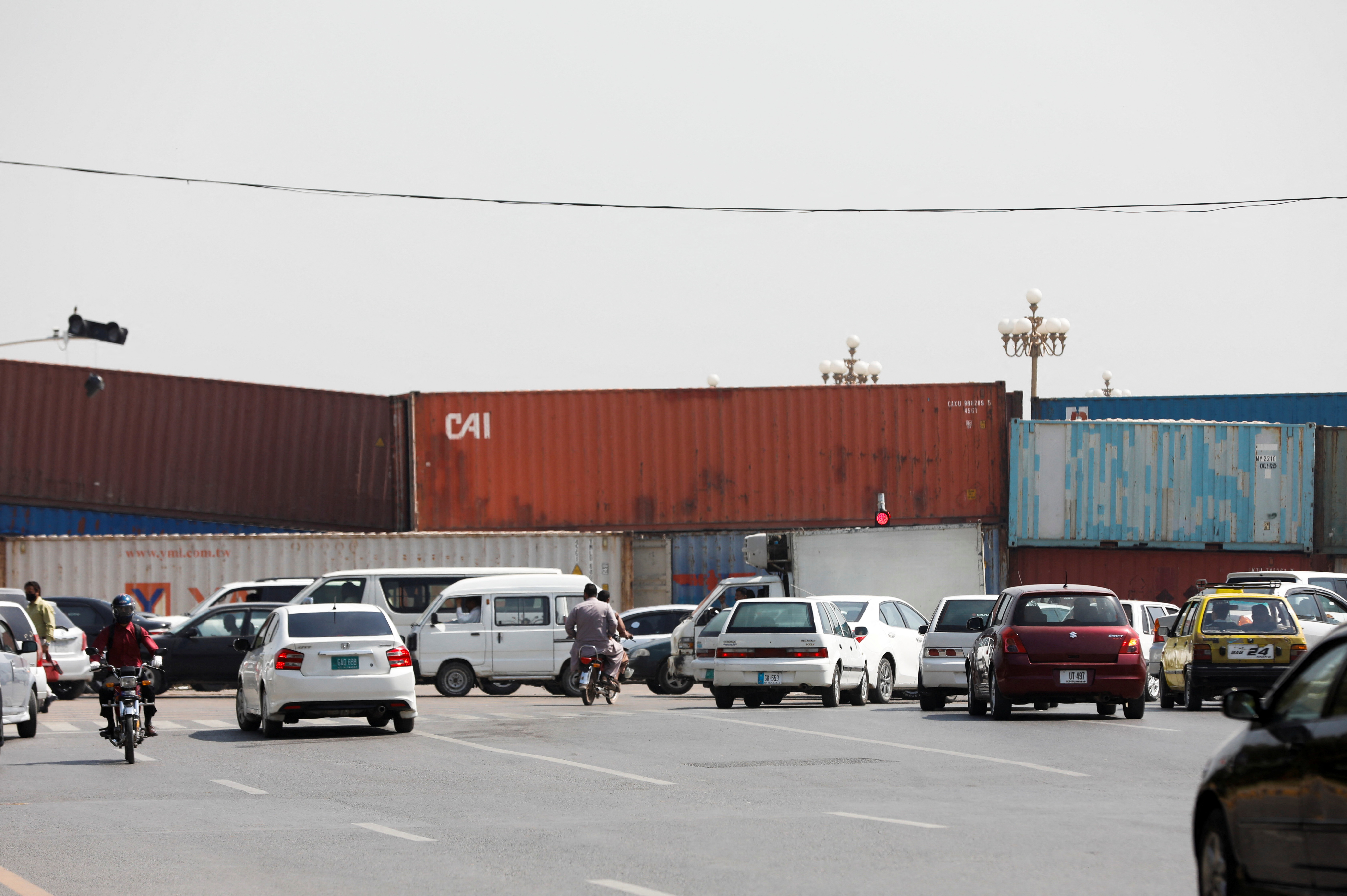 Vehicles move past shipping containers used to block the area leading towards the Red Zone, in Islamabad