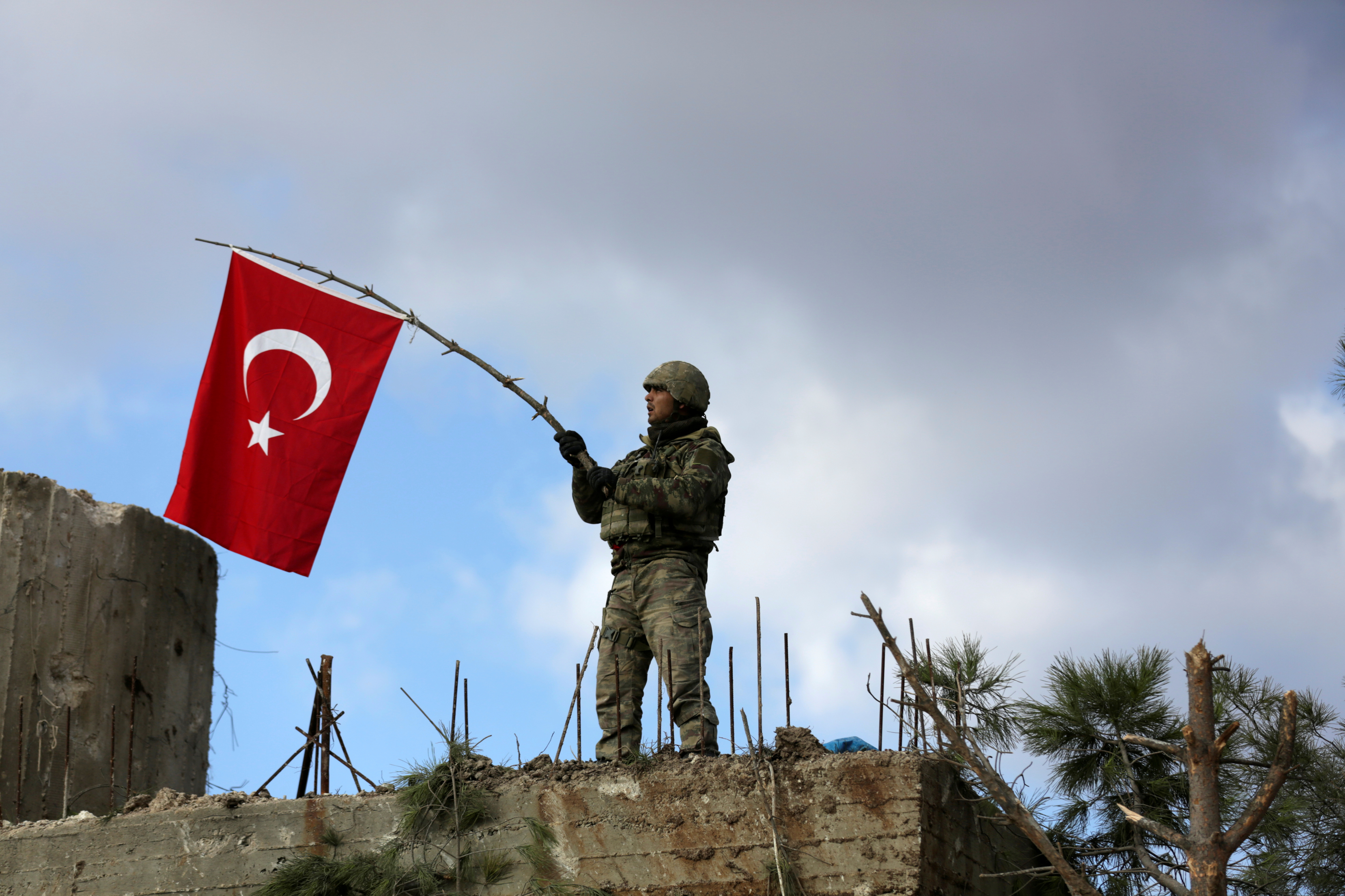 A Turkish soldier waves a flag on Mount Barsaya, northeast of Afrin