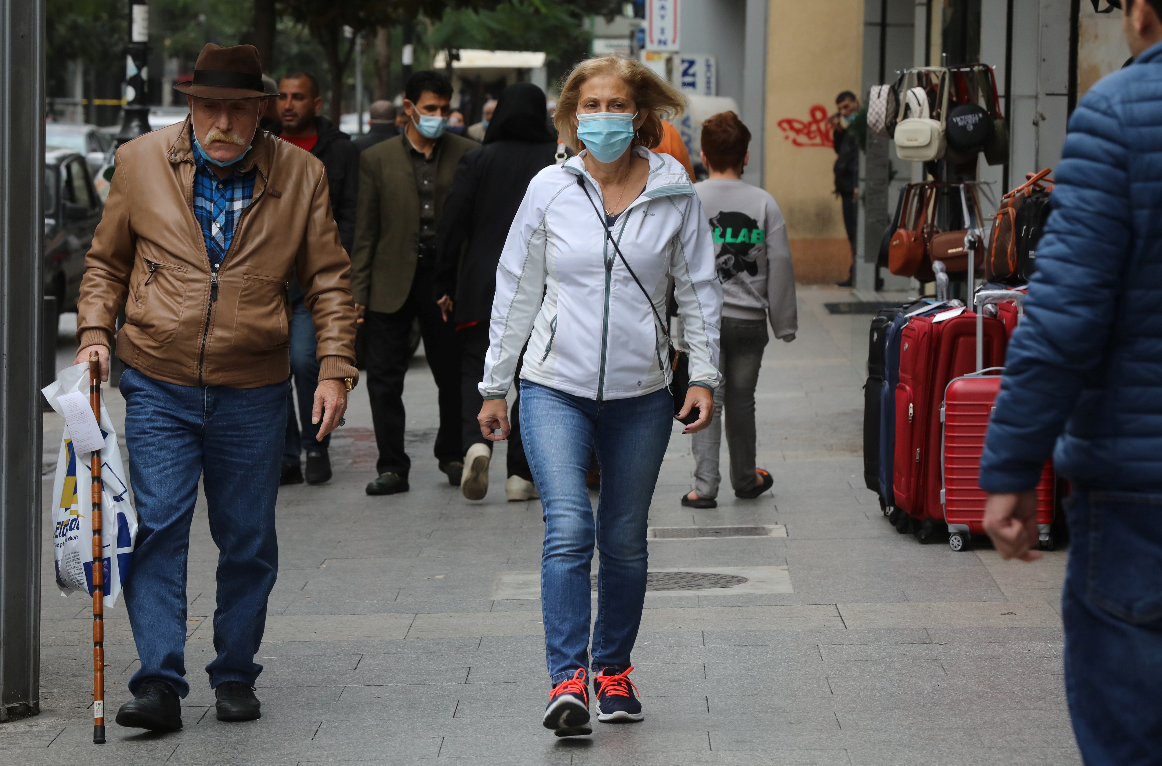 People wear face masks as they walk along a street in Beirut