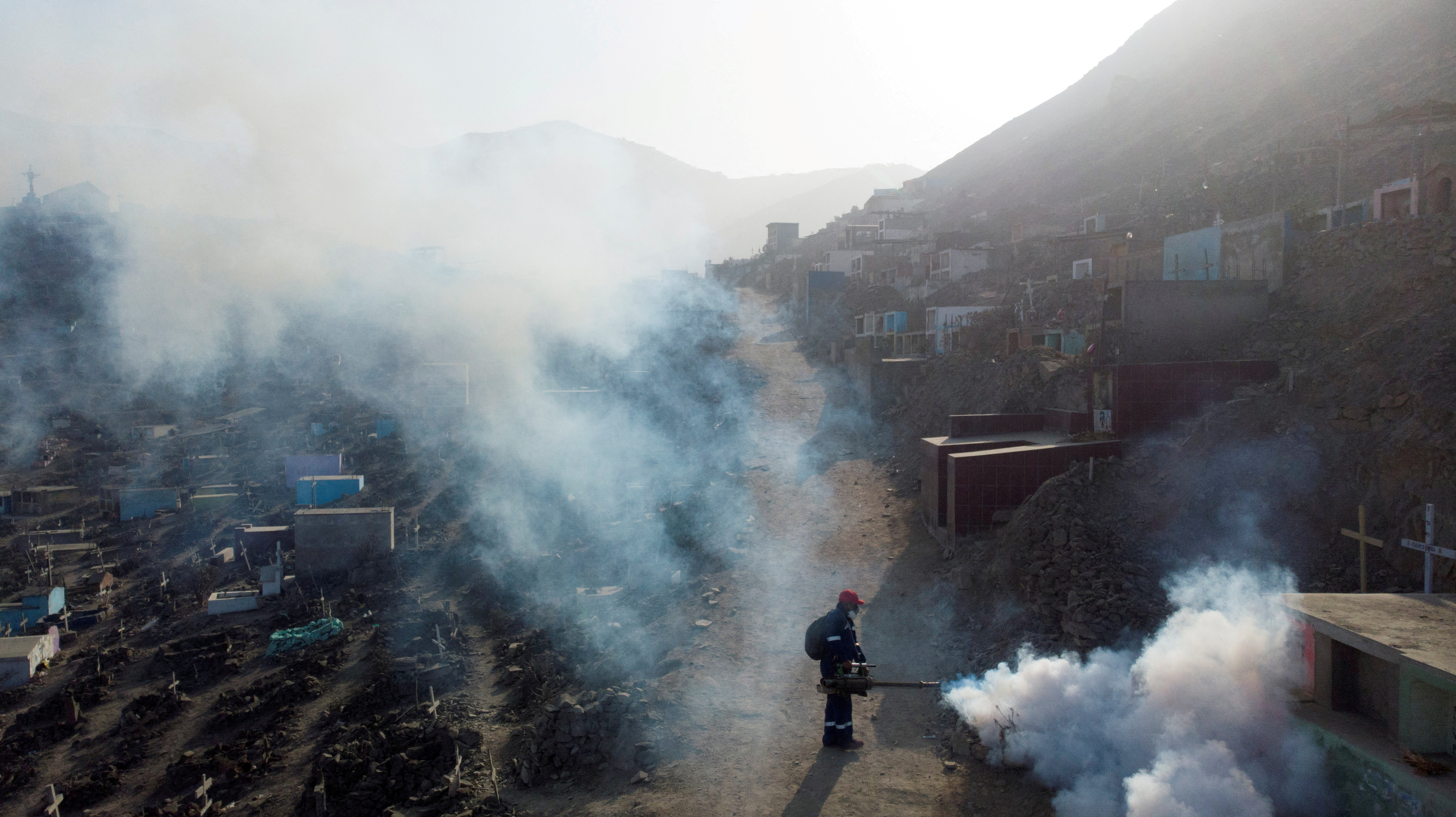 A health worker sprays fumigation vapour to stem the spread of dengue virus at the Nueva Esperanza cemetery in Lima