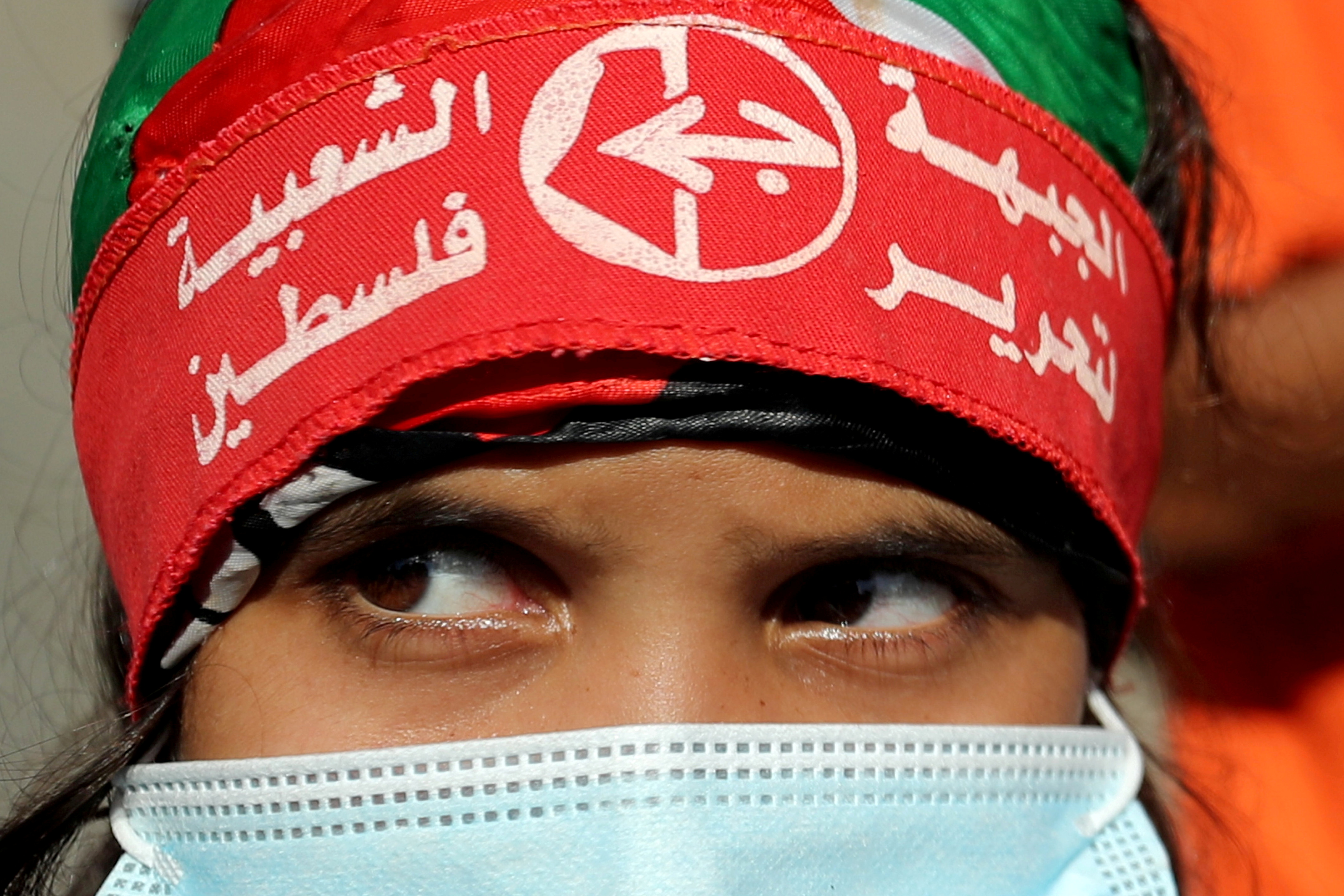A girl wearing a protective face mask and the headband of the Popular Front for the Liberation of Palestine (PFLP) looks on during a rally to show solidarity with hunger-striking Palestinian prisoner Maher Al-Akhras
