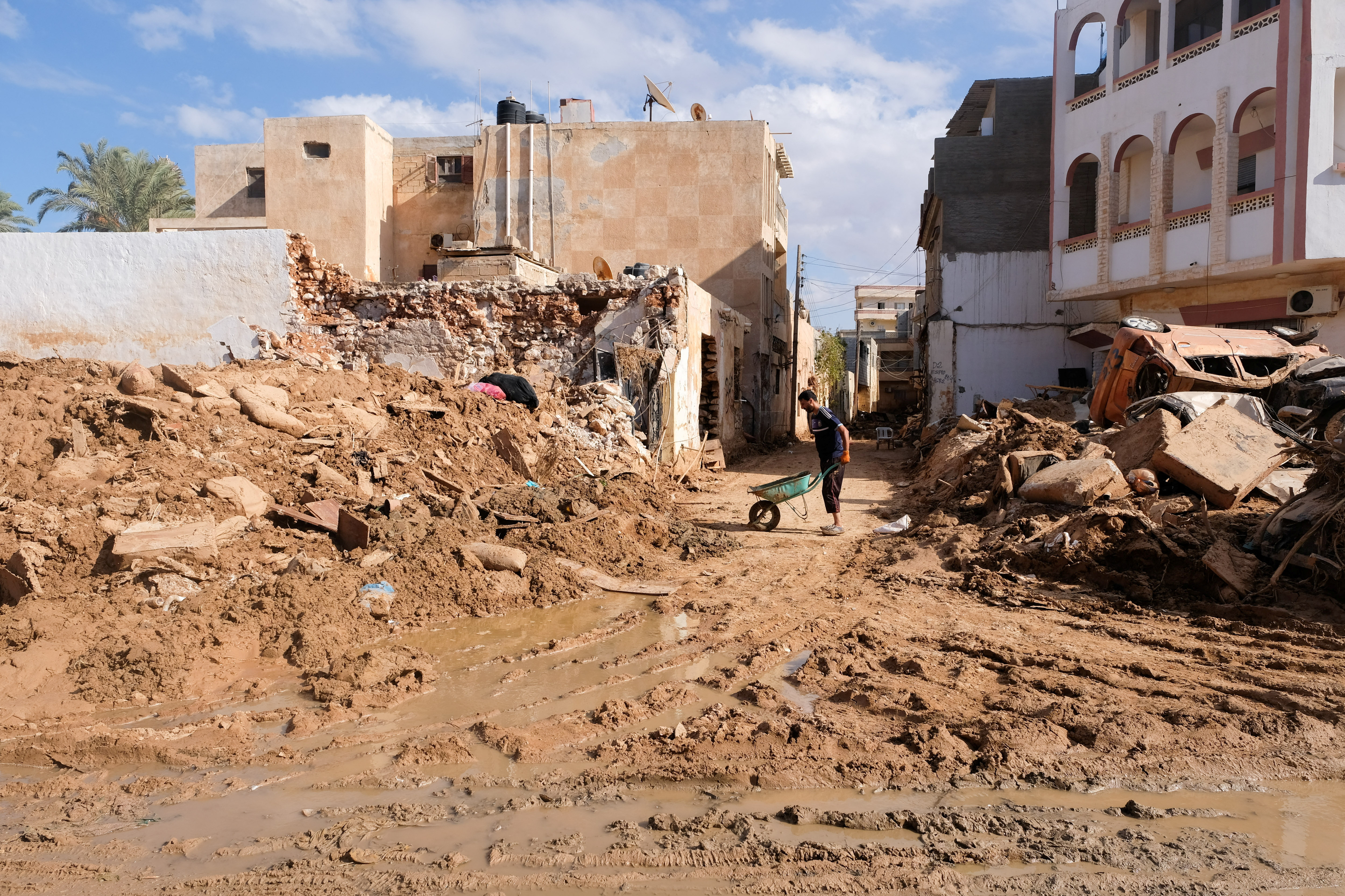 A man dumps mud collected while cleaning his house, which was affected by fatal floods, in Derna