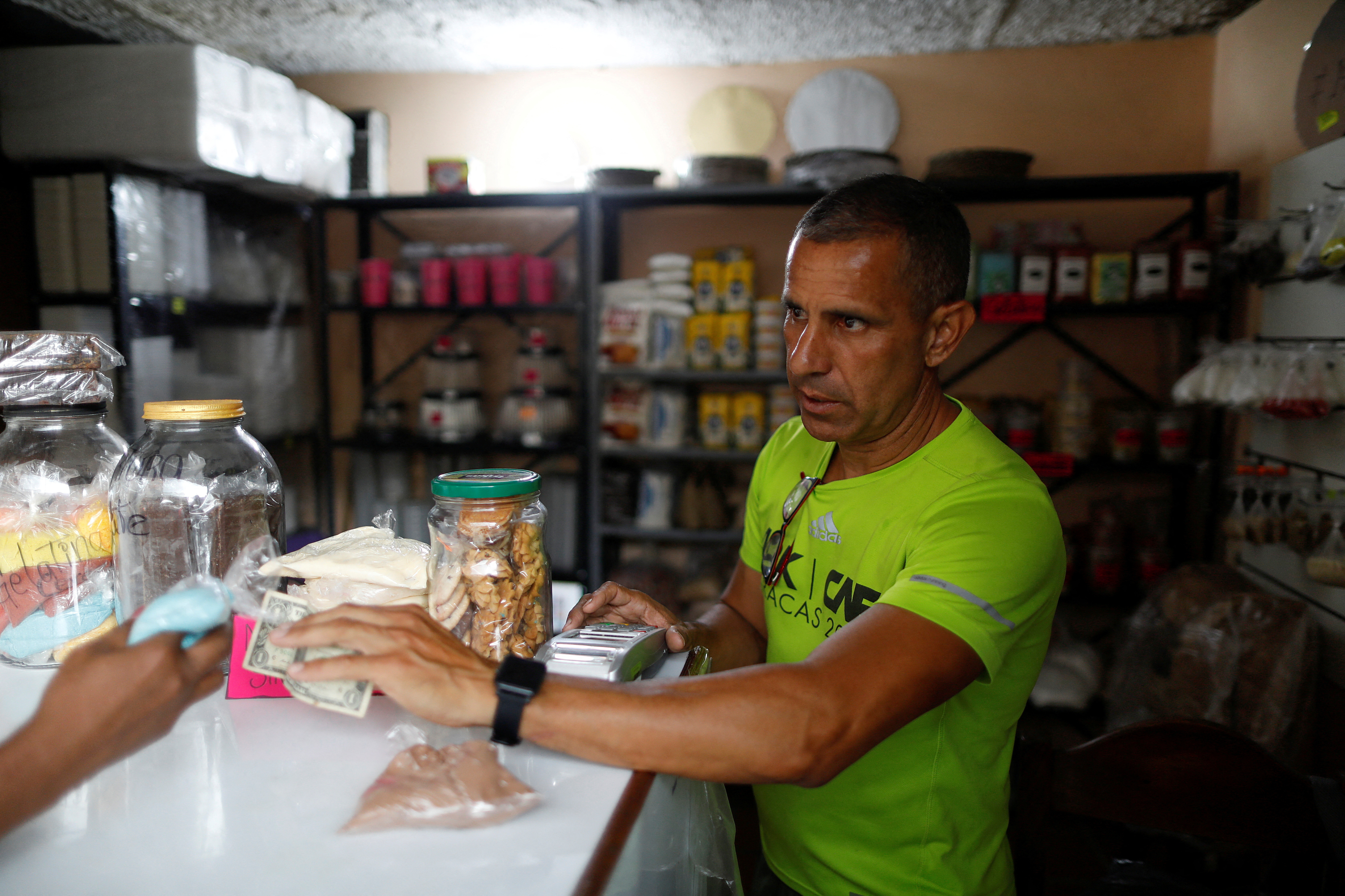 A worker receives a dollar cash payment in a store in a market in Caracas,
