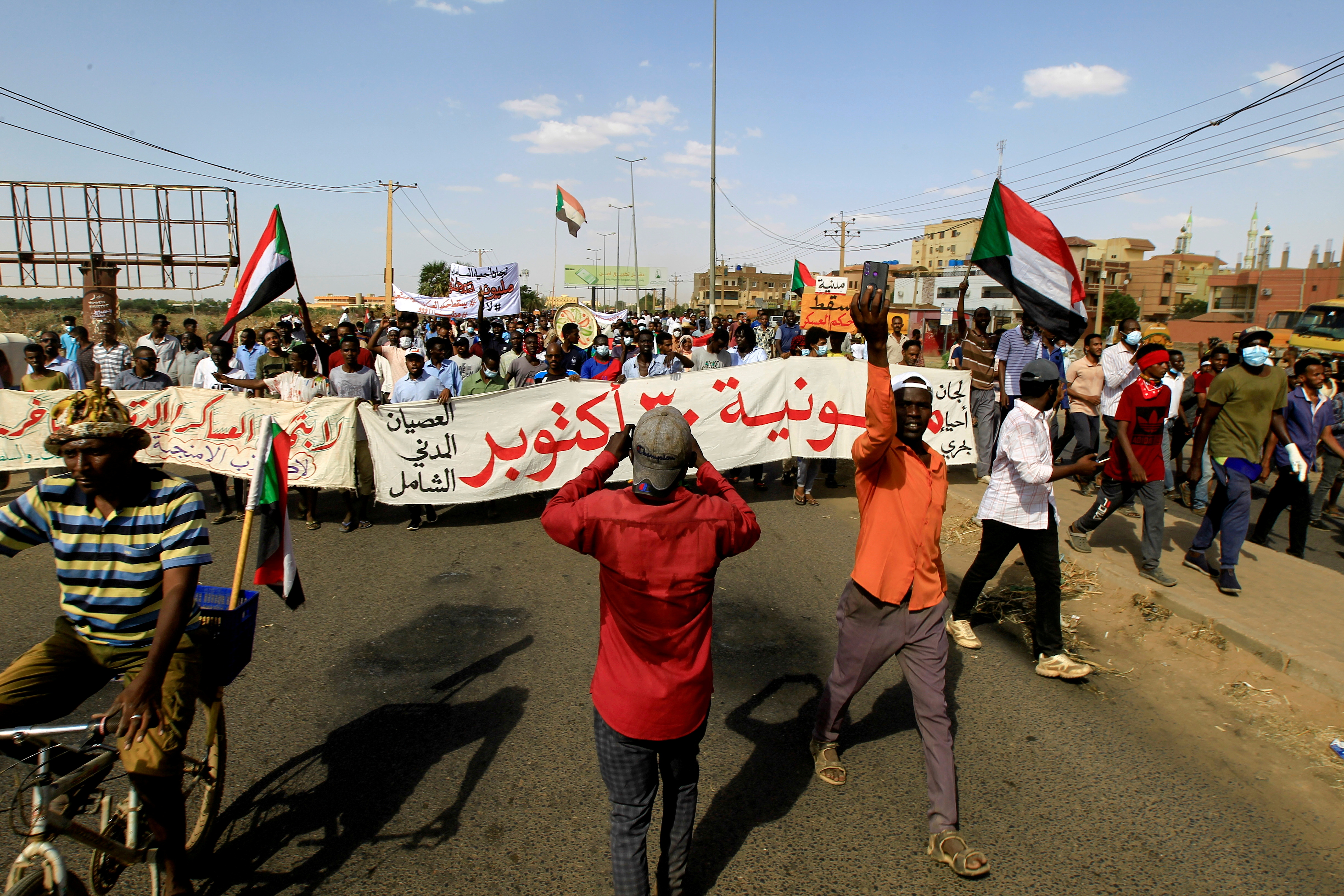  Protesters carry a banner and national flags as they march against the Sudanese military's recent seizure of power and ousting of the civilian government, in the streets of the capital Khartoum, Sudan October 30, 2021. REUTERS/Mohamed Nureldin/File Photo