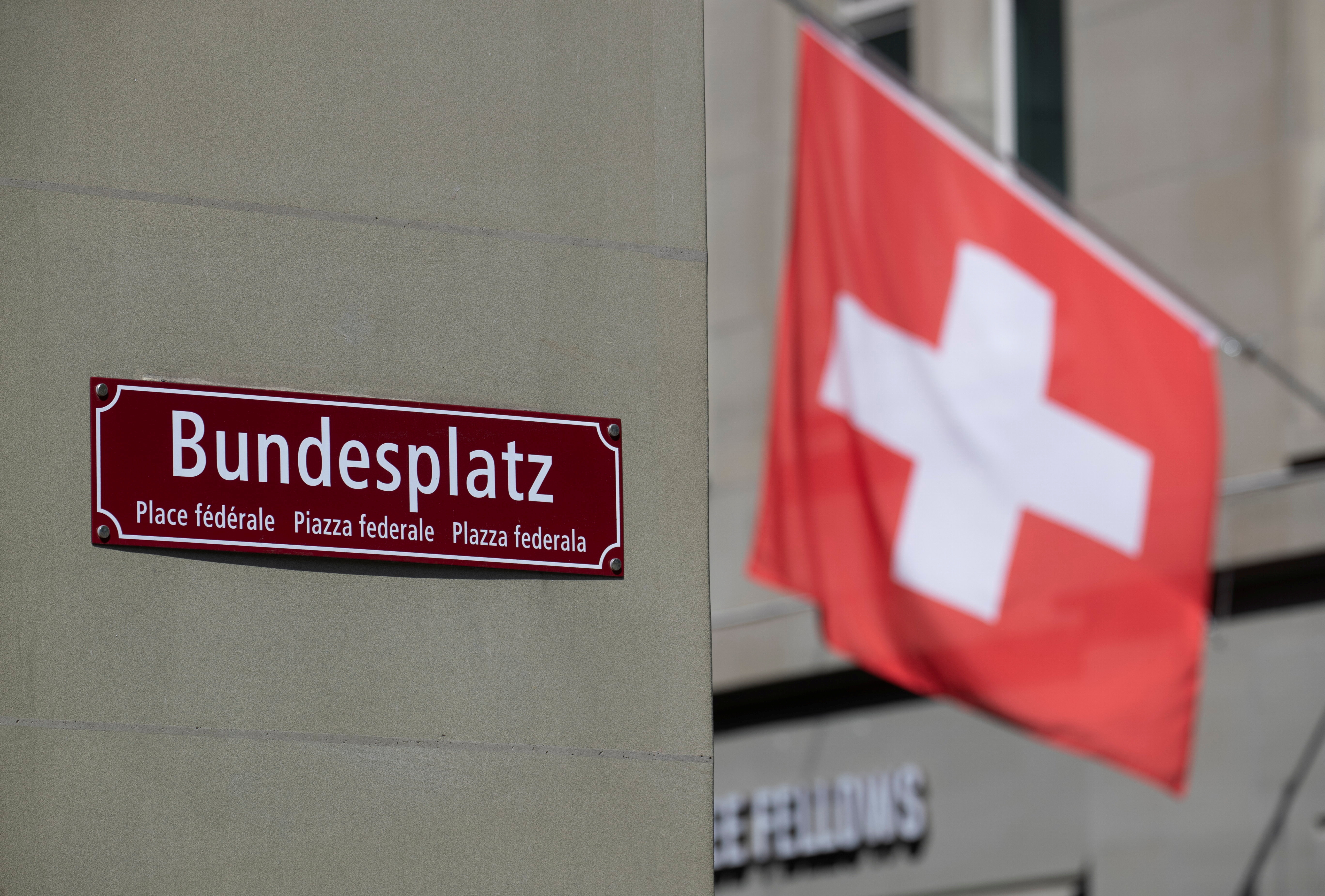 A Swiss national flag flies behind a sign marking the Bundesplatz square in Bern