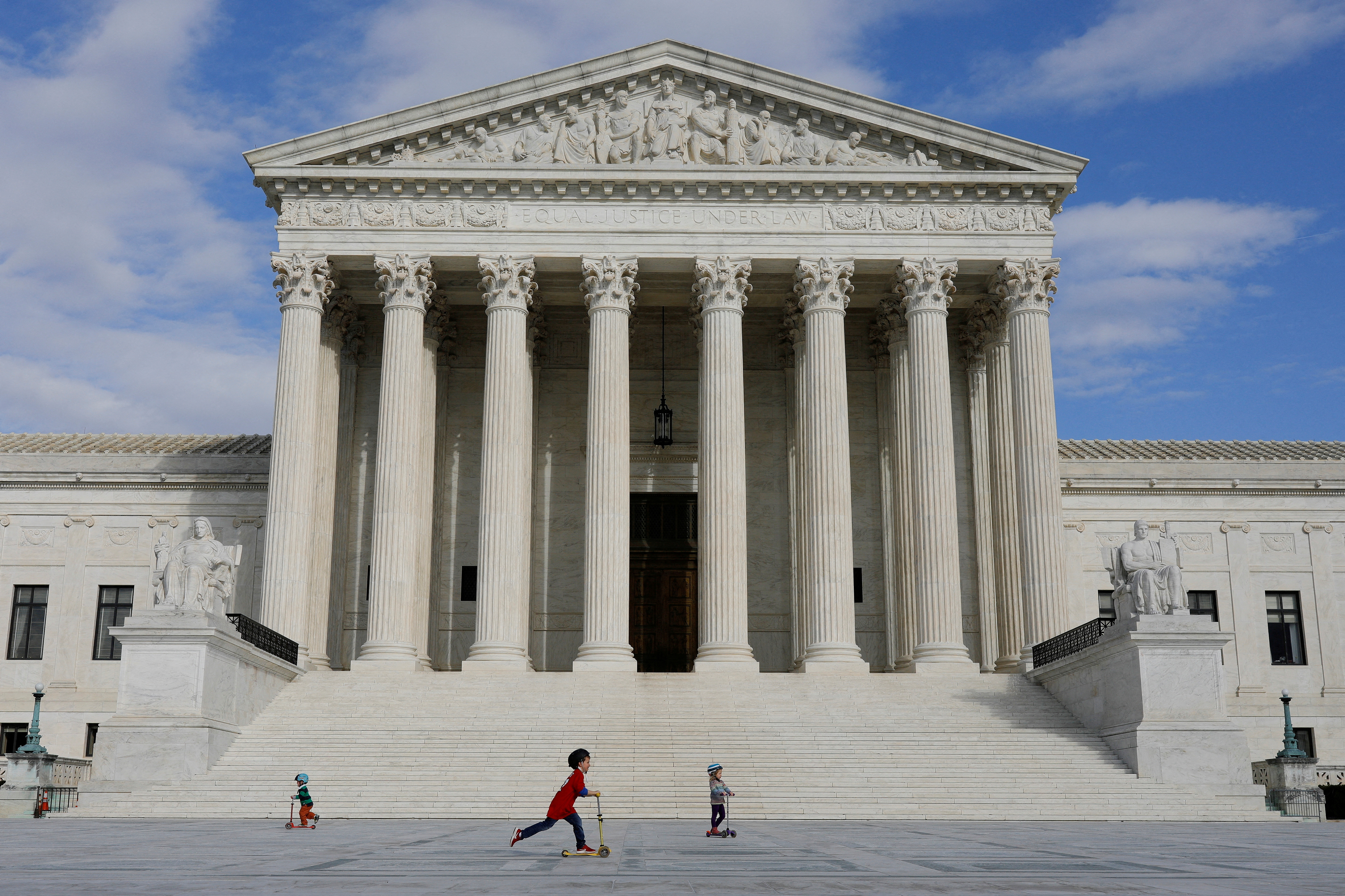 Children ride scooters across the plaza at the United States Supreme Court, following the government's notice to halt all building tours due to the (COVID-19) coronavirus, on Capitol Hill in Washington