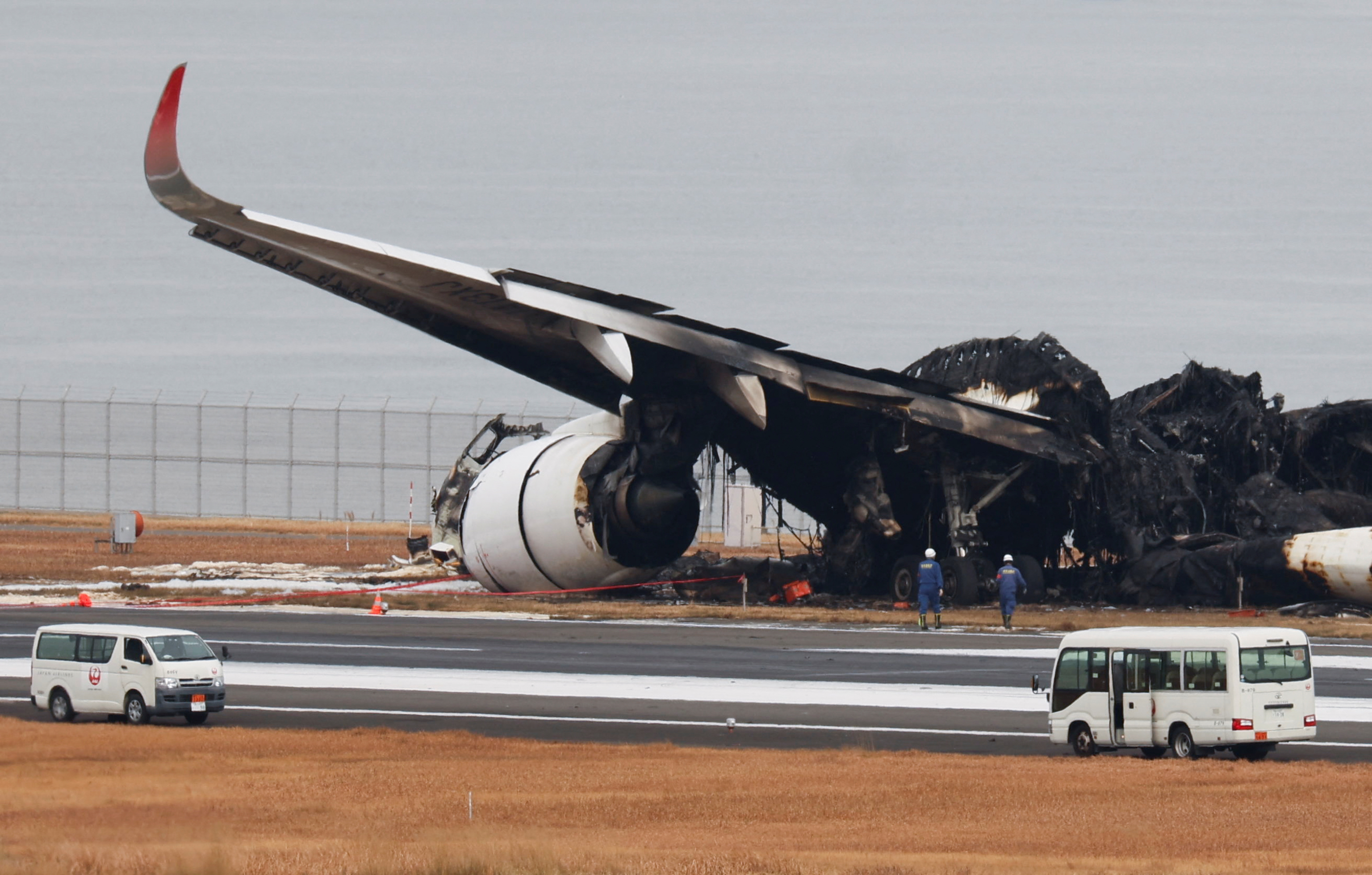 Officials investigate a burnt Japan Airlines (JAL) Airbus A350 plane after a collision with a Japan Coast Guard aircraft at Haneda International Airport in Tokyo