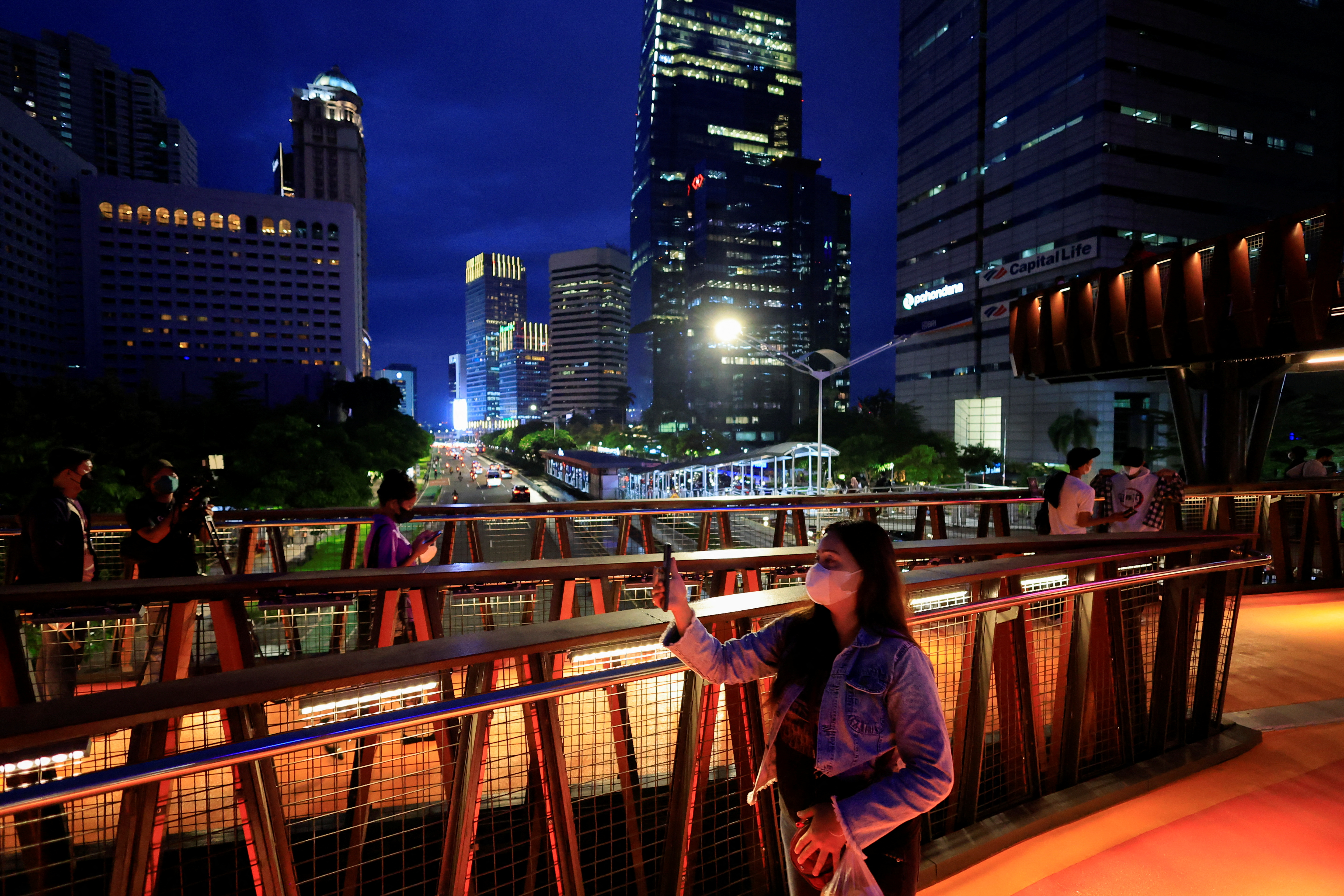 People enjoy a pedestrian bridge during the dusk amid of the COVID-19 pandemic in Jakarta