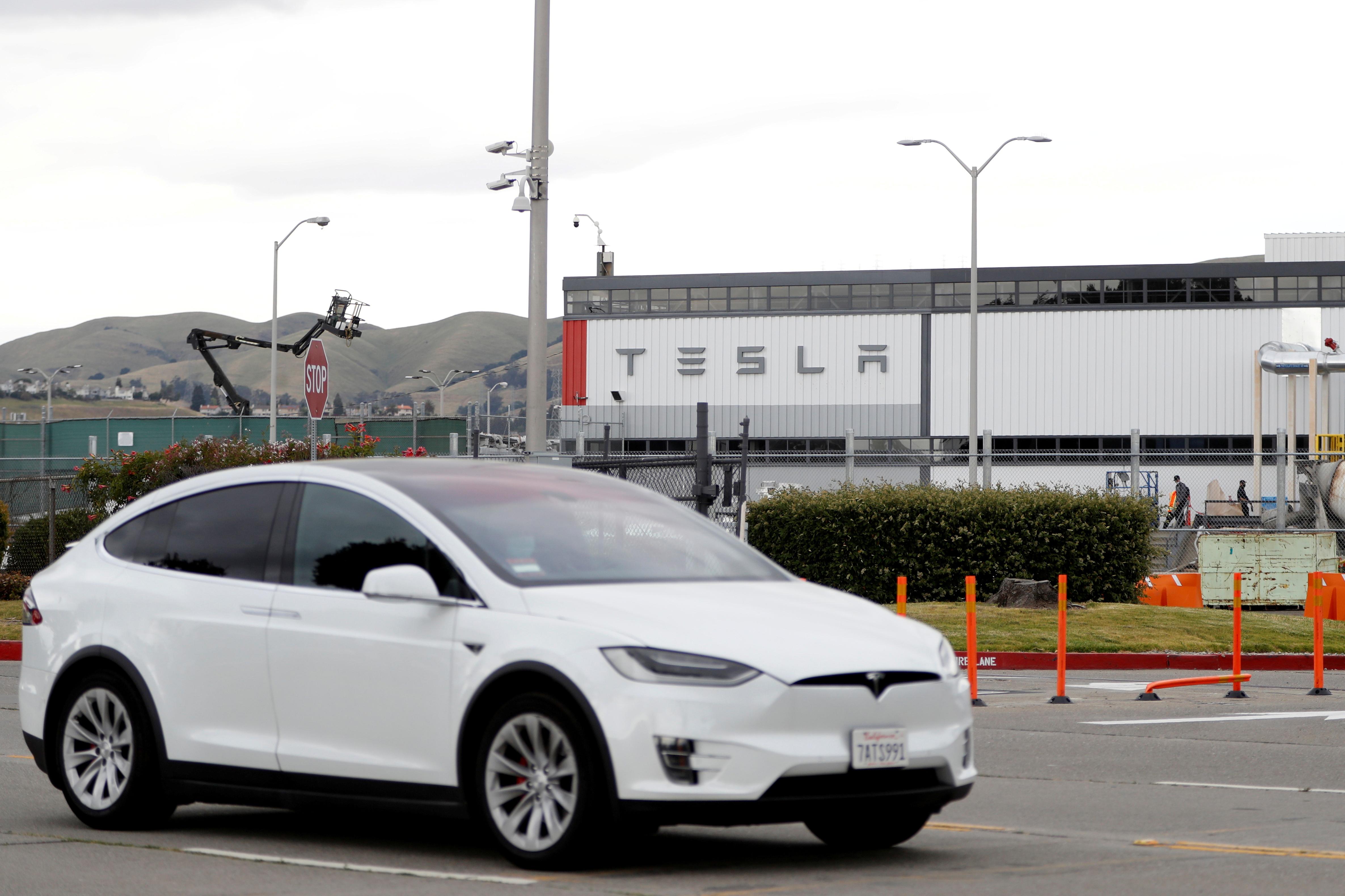 A Tesla vehicle drives past Tesla's primary vehicle factory after CEO Elon Musk announced he was defying local officials' coronavirus disease (COVID-19) restrictions by reopening the plant in Fremont, California, U.S. May 11, 2020. REUTERS/Stephen Lam/File Photo