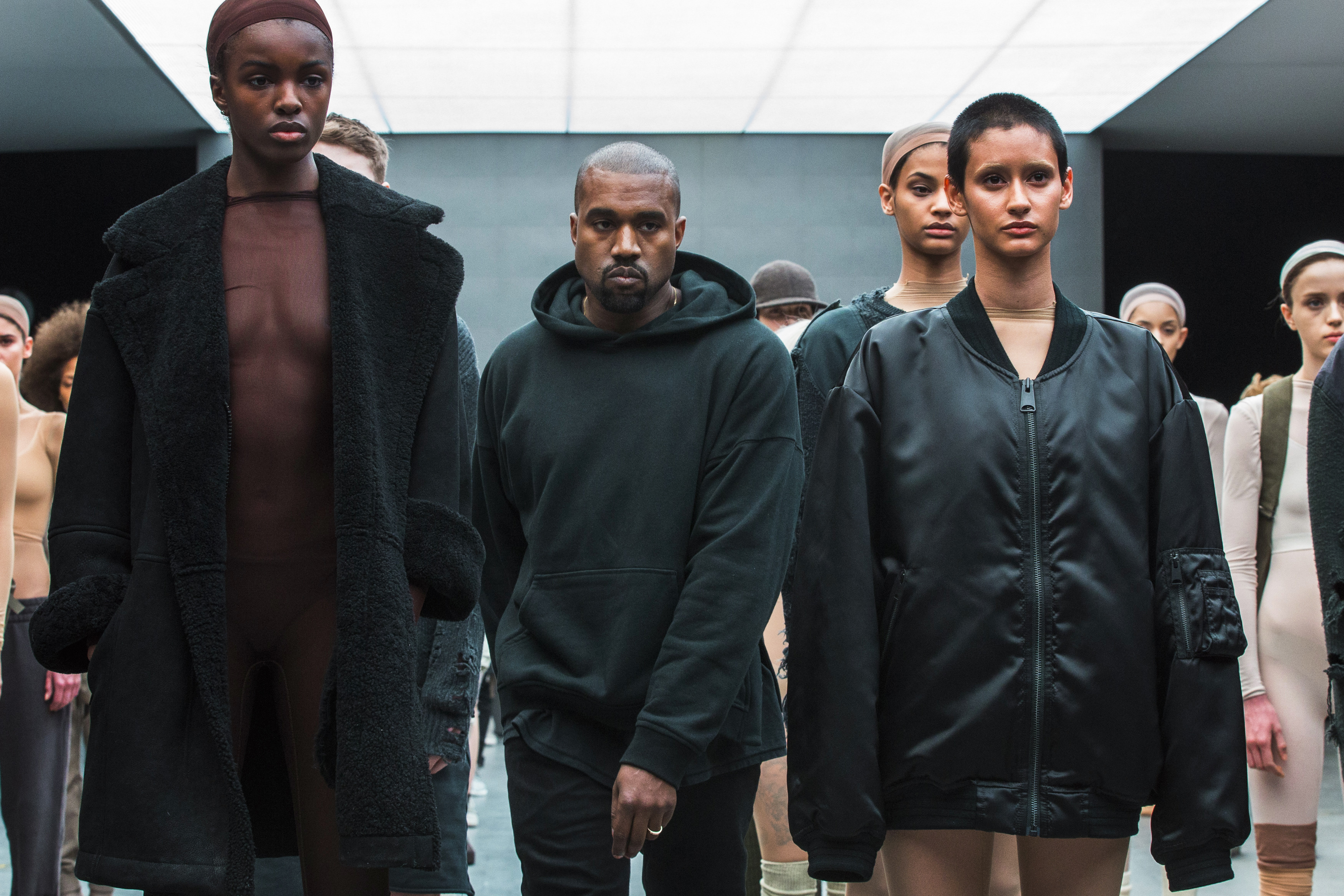 Singer Kanye West walks past models after presenting his Fall/Winter 2015 partnership line with Adidas 