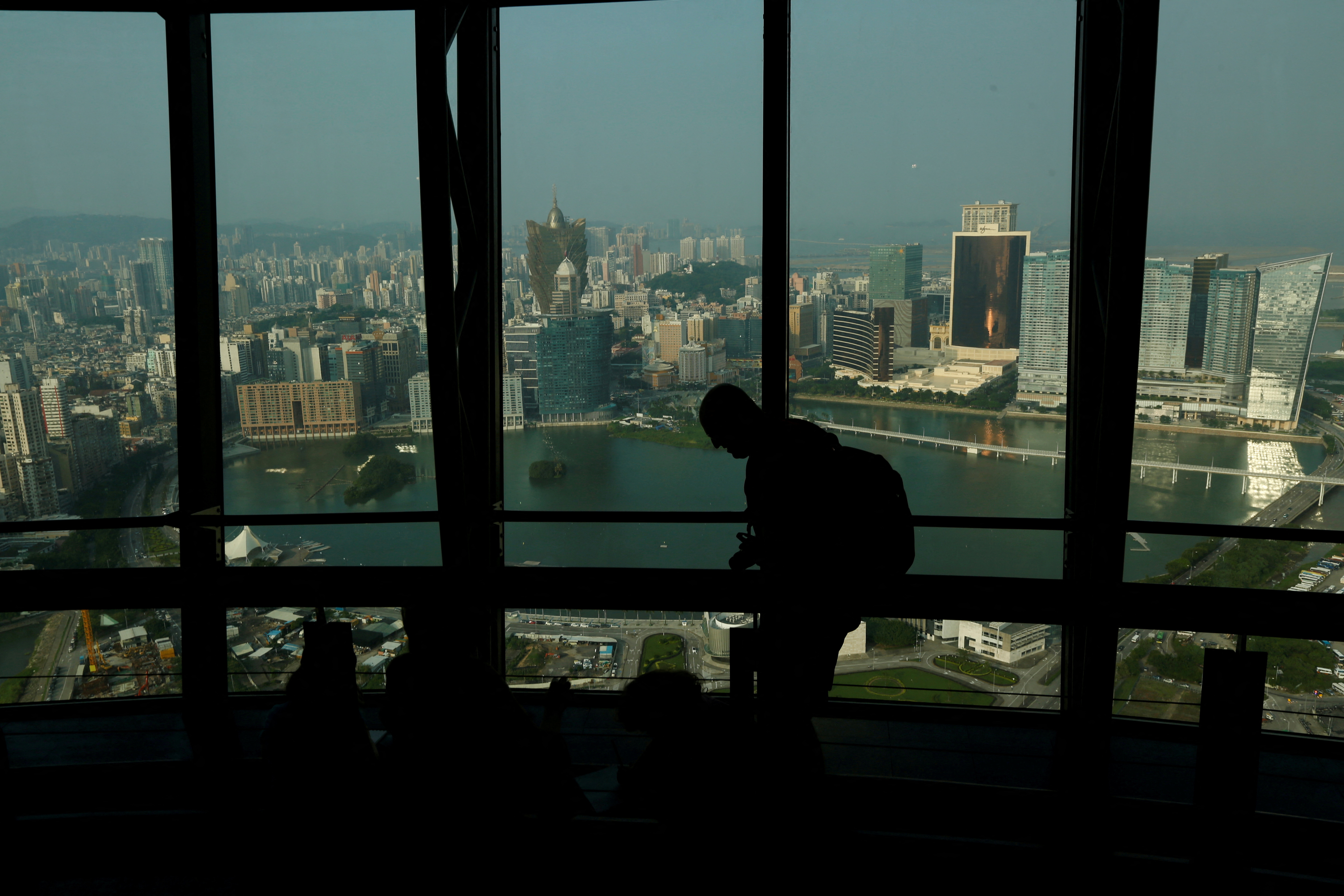 A visitor walks inside Macau Tower overlooking a general view of Macau peninsula