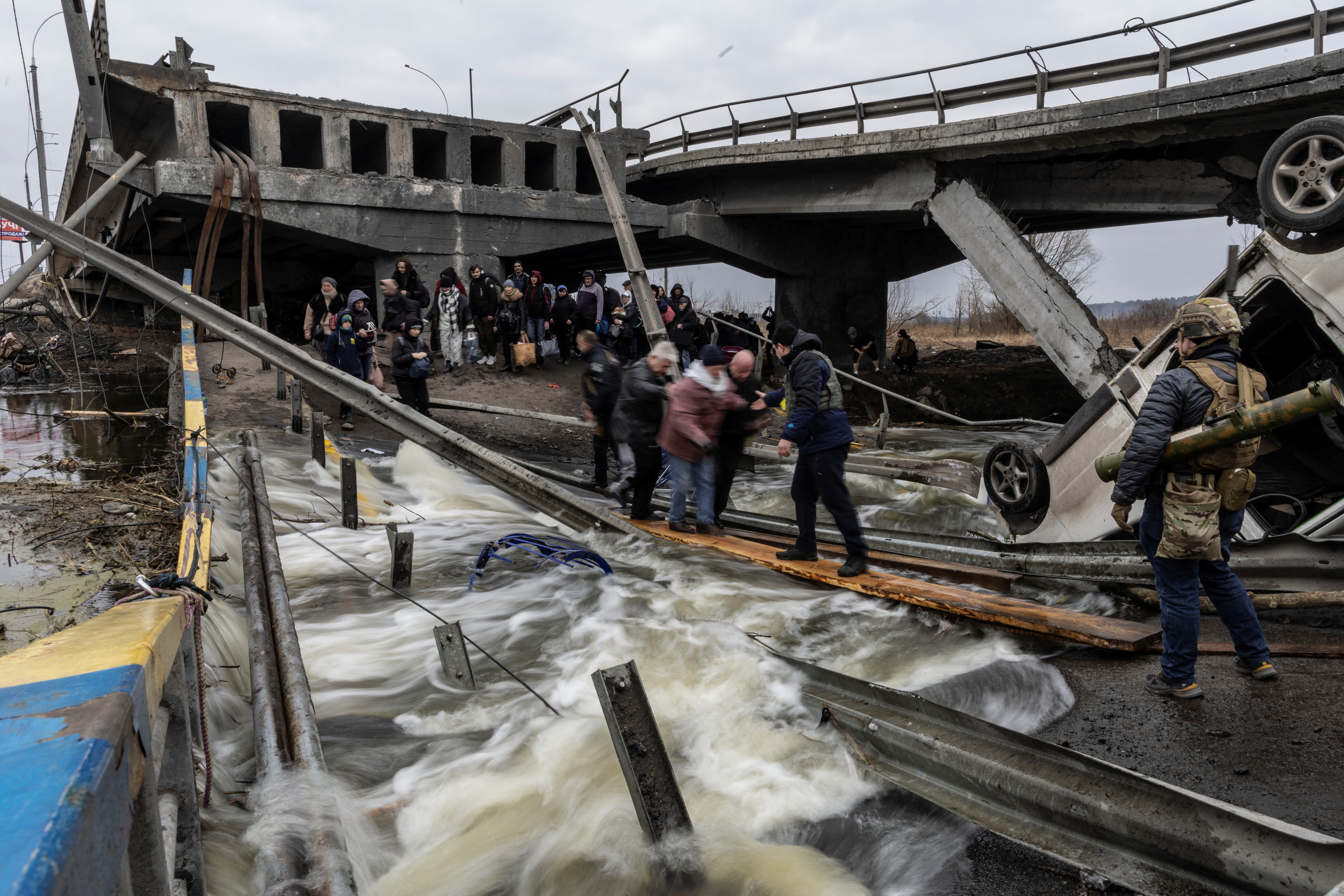 Local residents cross a destroyed bridge as they evacuate from the town of Irpin, after days of heavy shelling on the only escape route used by locals, while Russian troops advance towards the capital, in Irpin, near Kyiv