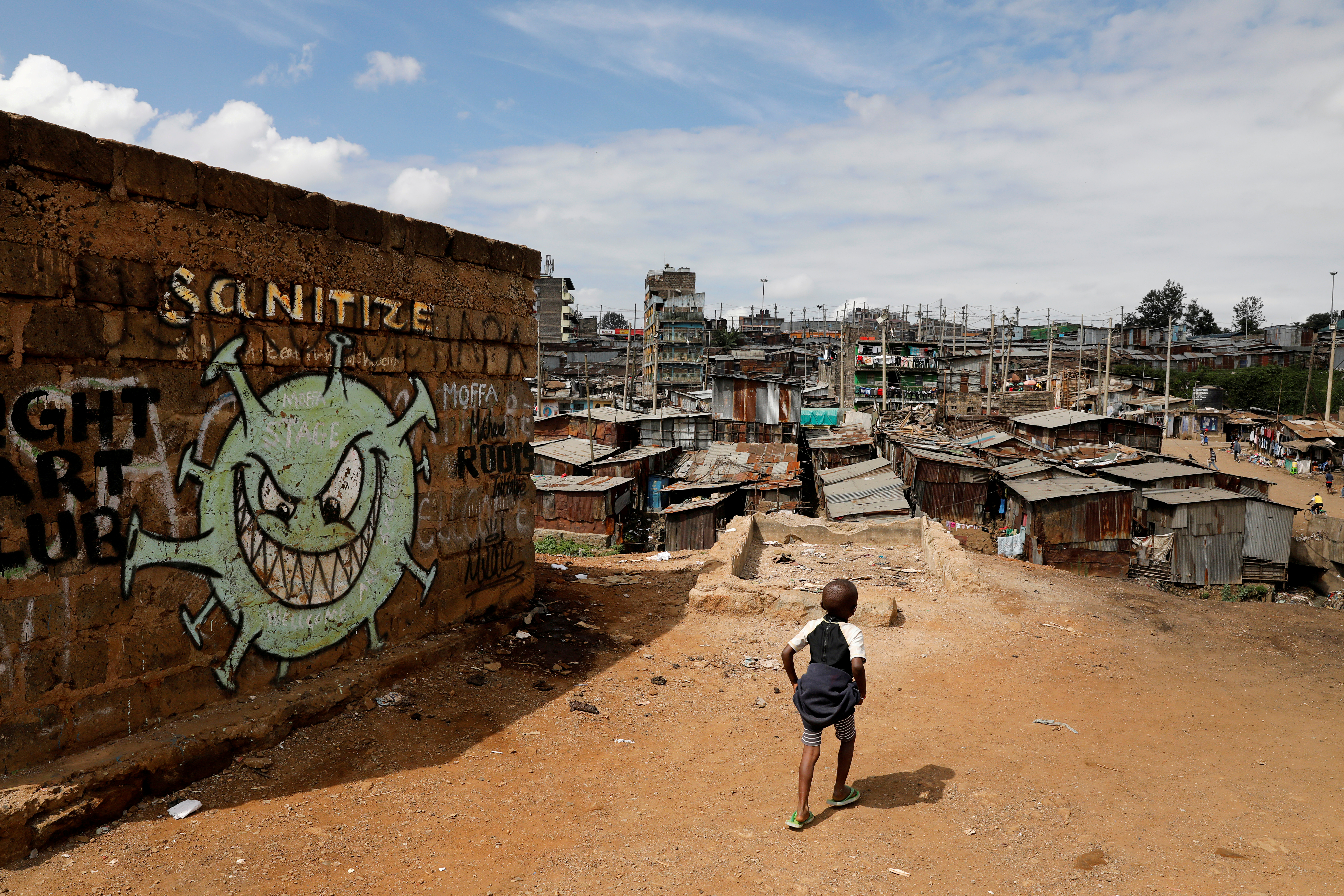 FILE PHOTO: A boy walks in front of graffiti promoting the fight against the coronavirus disease in the Mathare slums of Nairobi