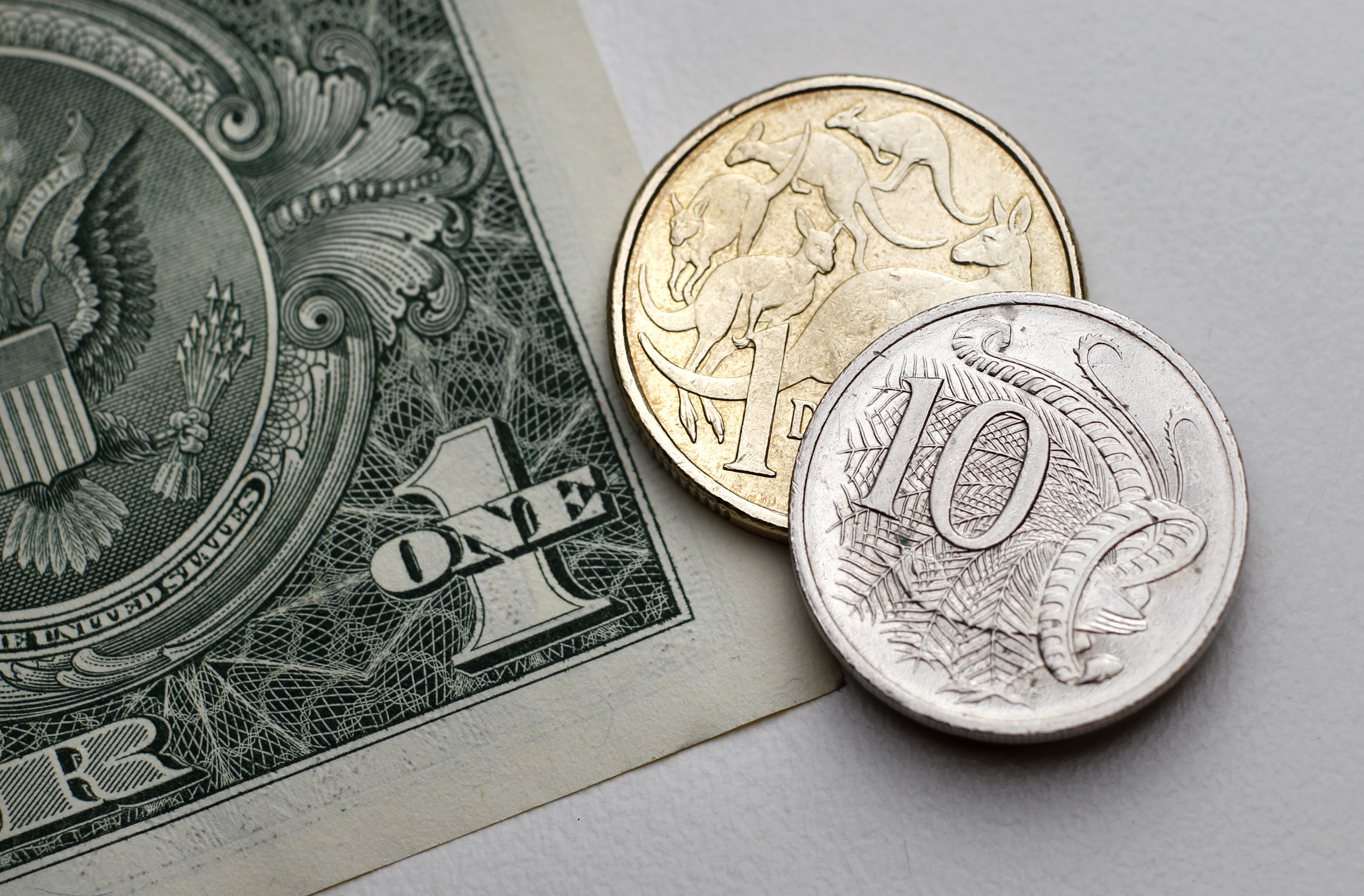 Photo illustration shows one dollar and 10 cents in Australian currency sitting atop a U.S. one dollar note in Sydney