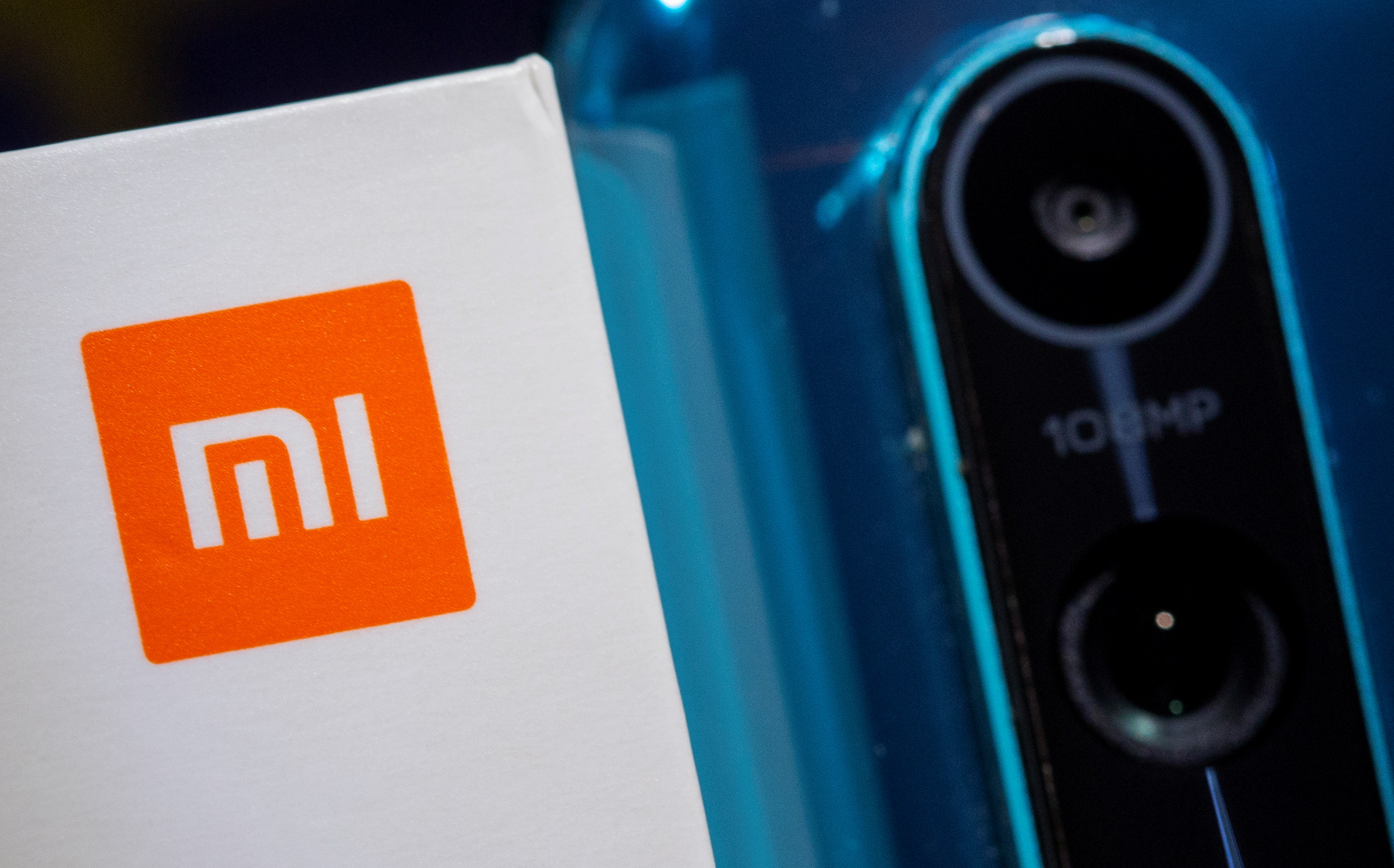 Xiaomi logo is seen next to a smartphone of the same brand in this illustration