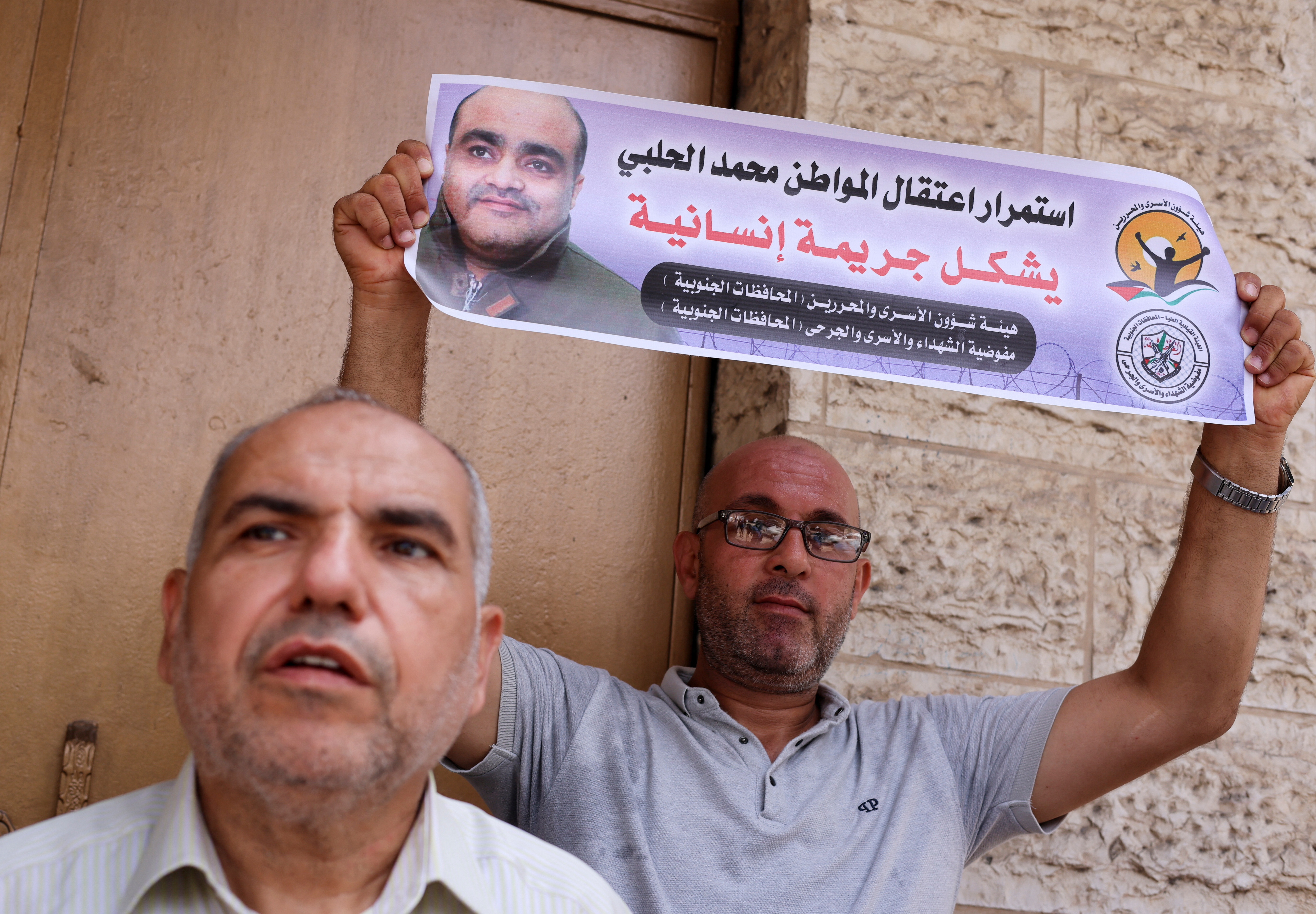 A man holds a picture of Mohammad El Halabi, during a solidarity gathering following an Israeli court decision to sentence him for 12 years, outside the office of the International Committee of the Red Cross in Gaza City