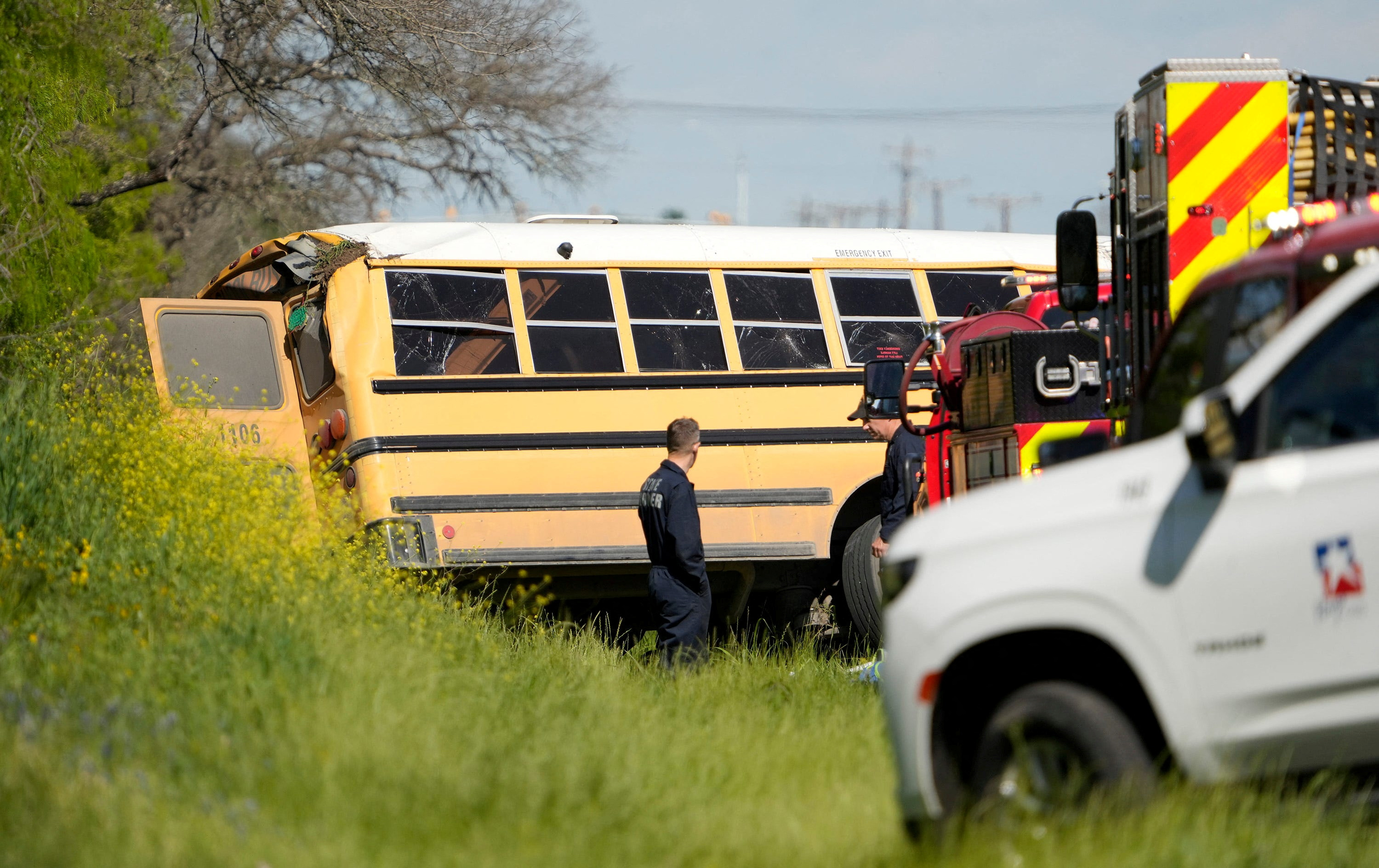 Officials look at a school bus that was carrying Tom Green Elementary pre-K students when it crashed in Austin