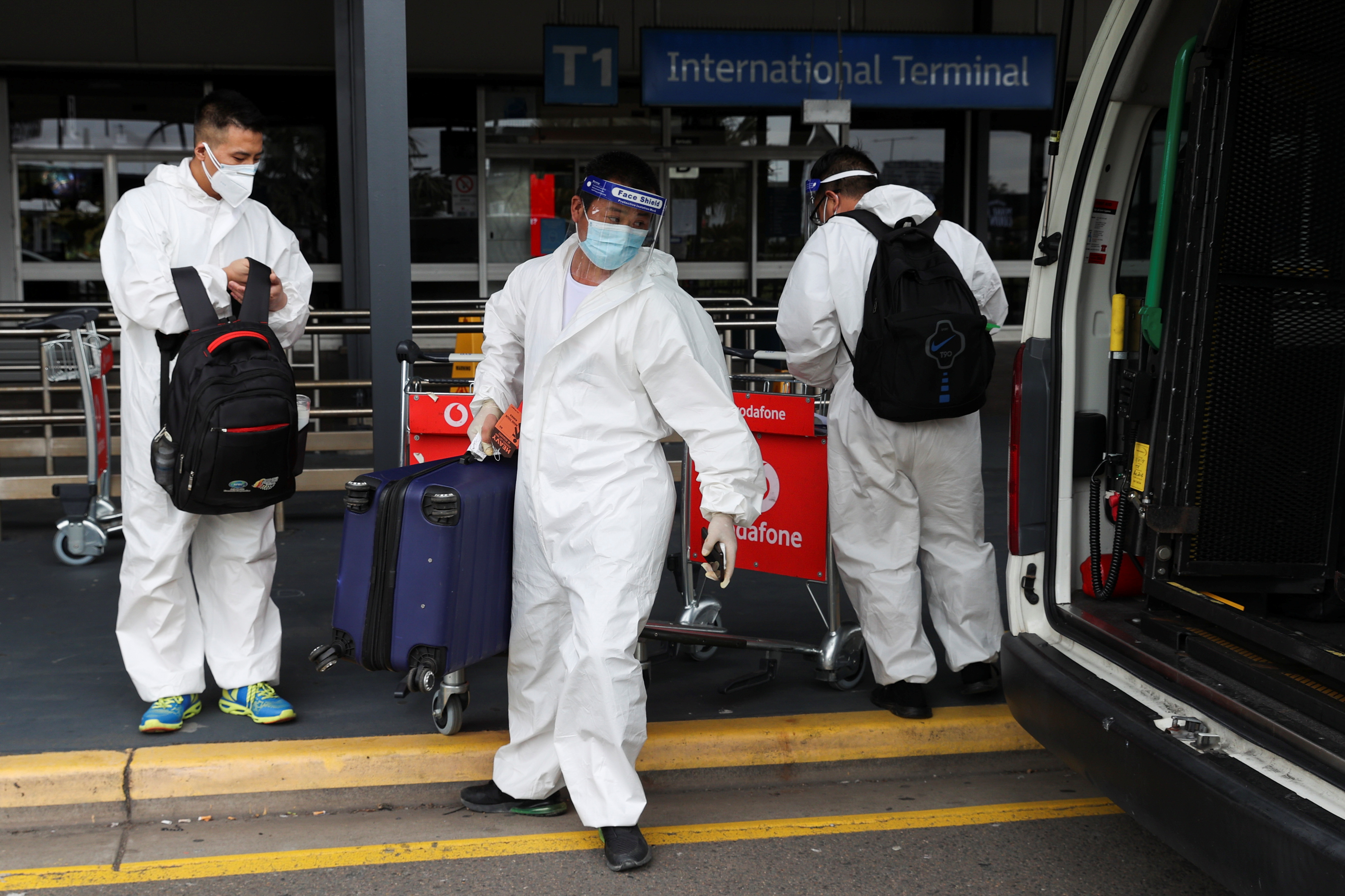Travellers in personal protective equipment load luggage into a taxi outside the international terminal at Sydney Airport, as countries react to the new coronavirus Omicron variant amid the coronavirus disease (COVID-19) pandemic, in Sydney, Australia, November 29, 2021.  REUTERS/Loren Elliott