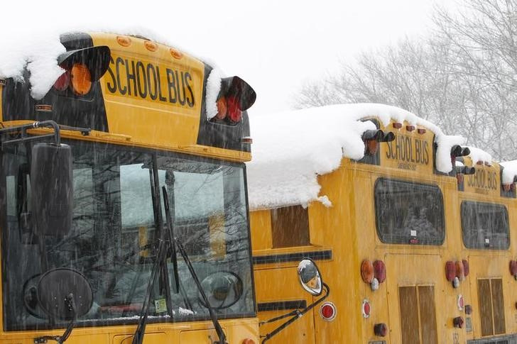 Snow falls over school buses parked at Great Falls Elementary School in Great Falls, Virginia,