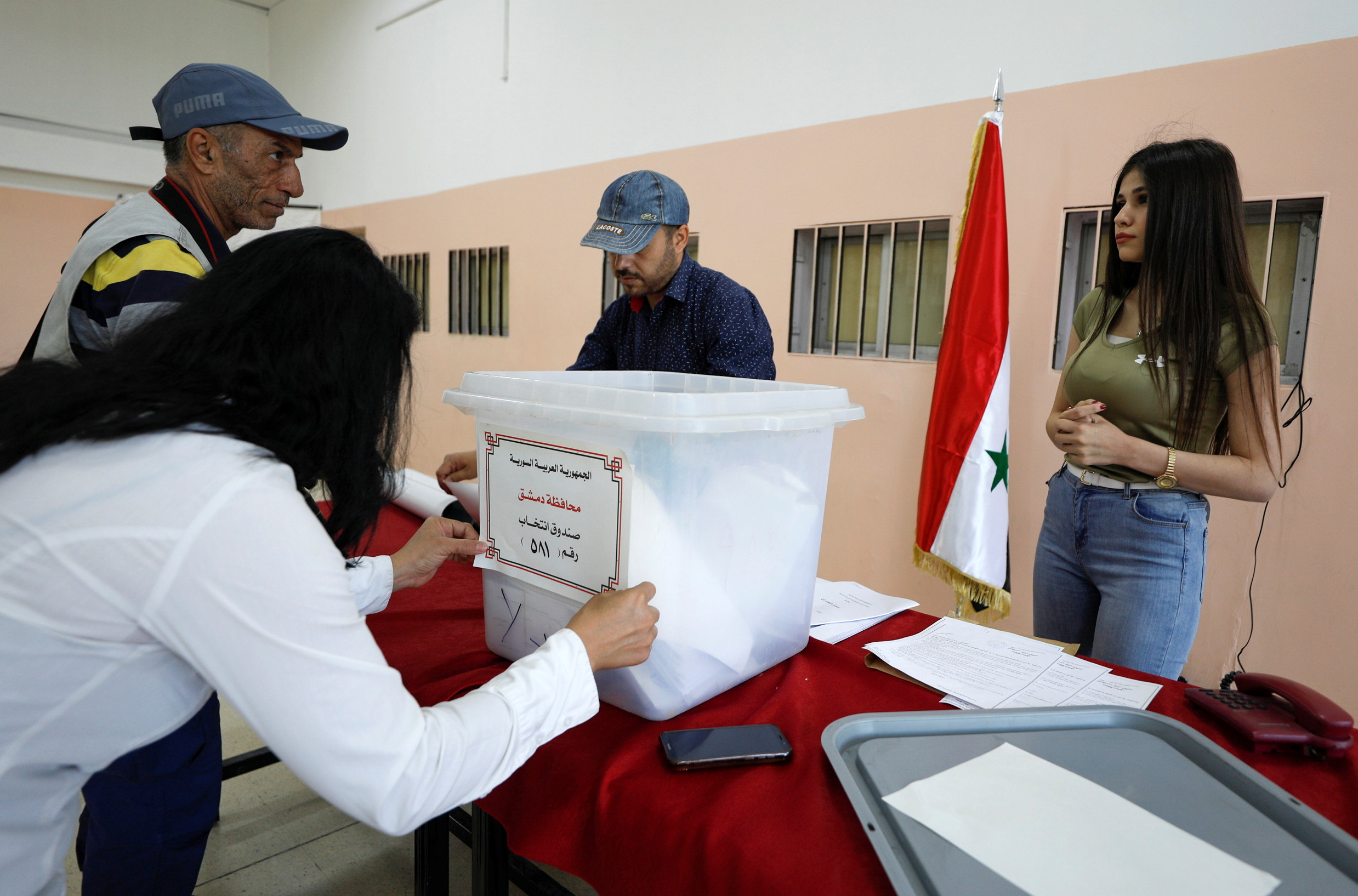 A woman prepares a ballot box during the presidential elections at a polling centre in Damascus