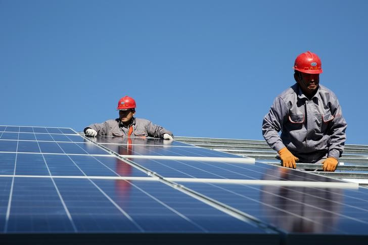 Workers install solar panels at a residential home in a village in Dongying