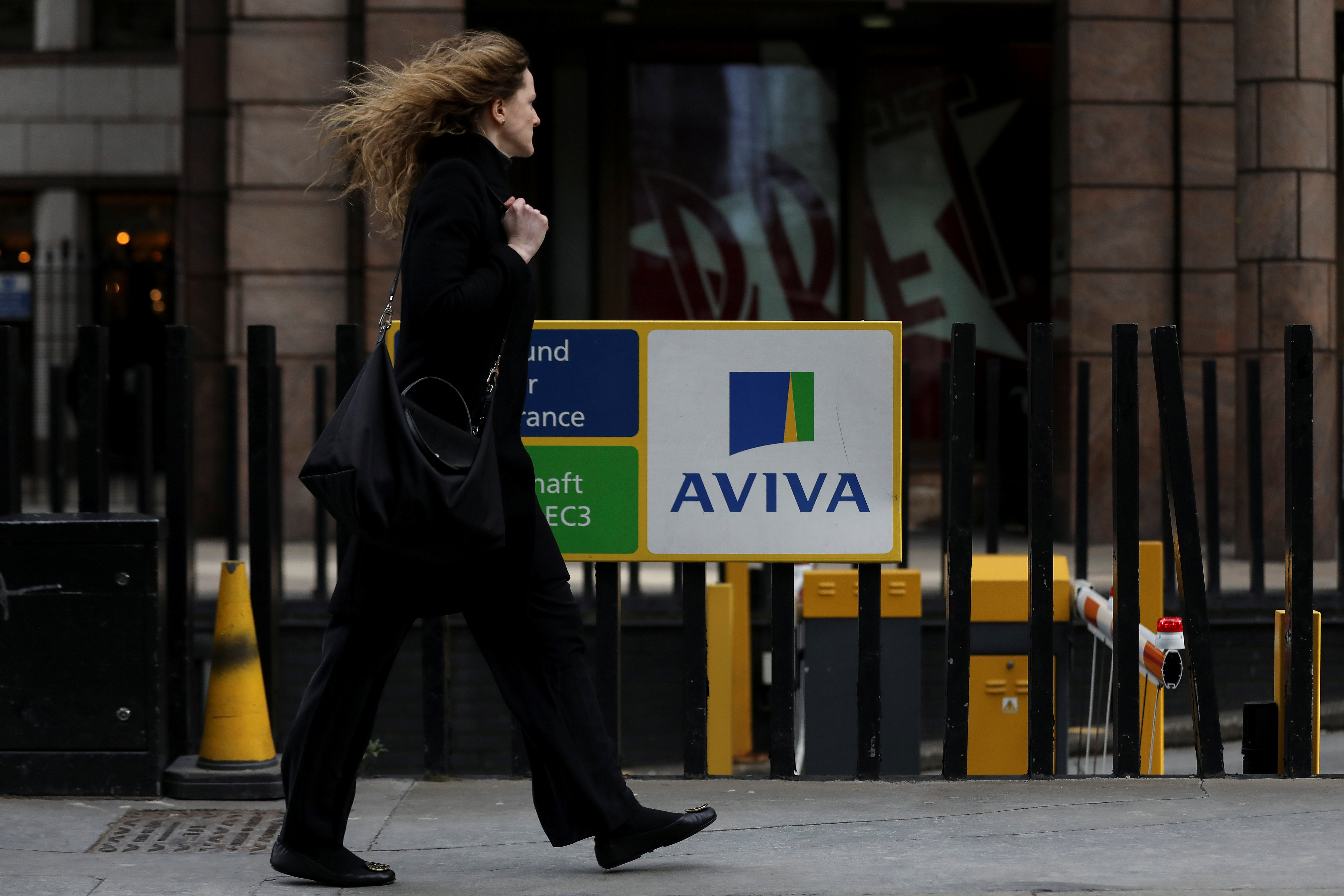 A pedestrians walks past the Aviva logo outside the company head office in the city of London