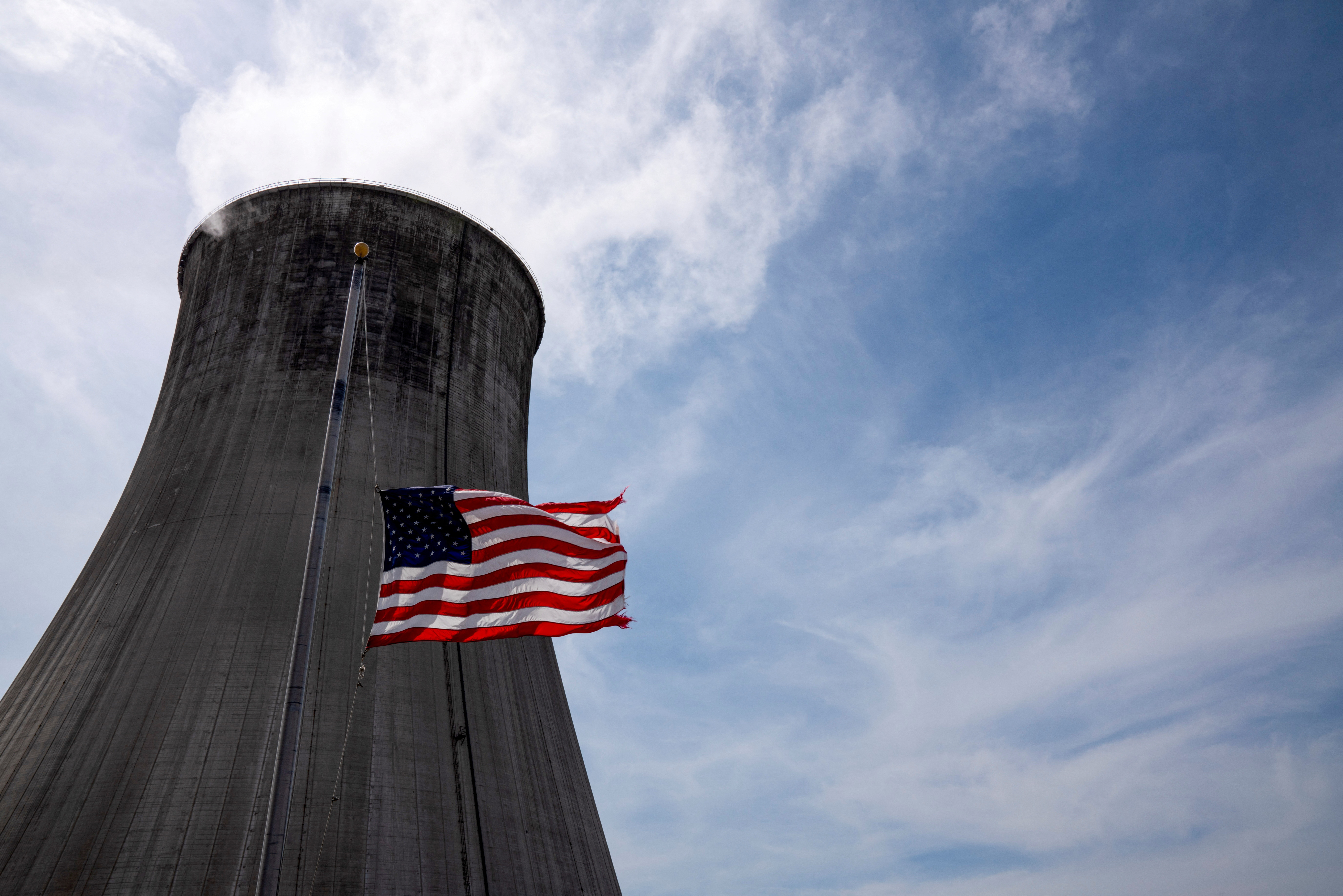 The US flag flies at half mast in front of a coal-fired power plant's cooling tower at Duke Energy's Crystal River Energy Complex