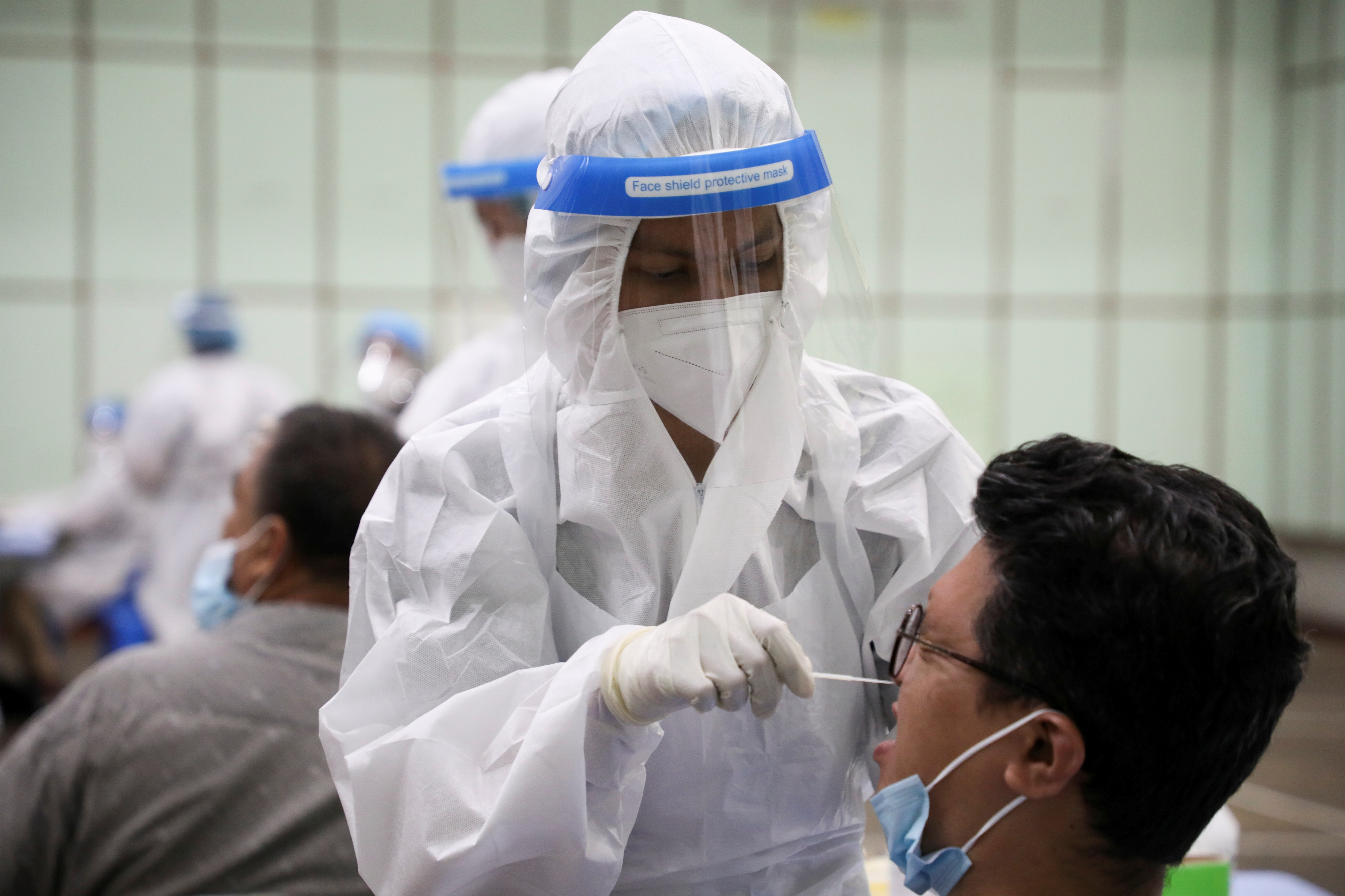 A medical worker collects a swab sample from a man to be tested for COVID-19, in Kuala Lumpur