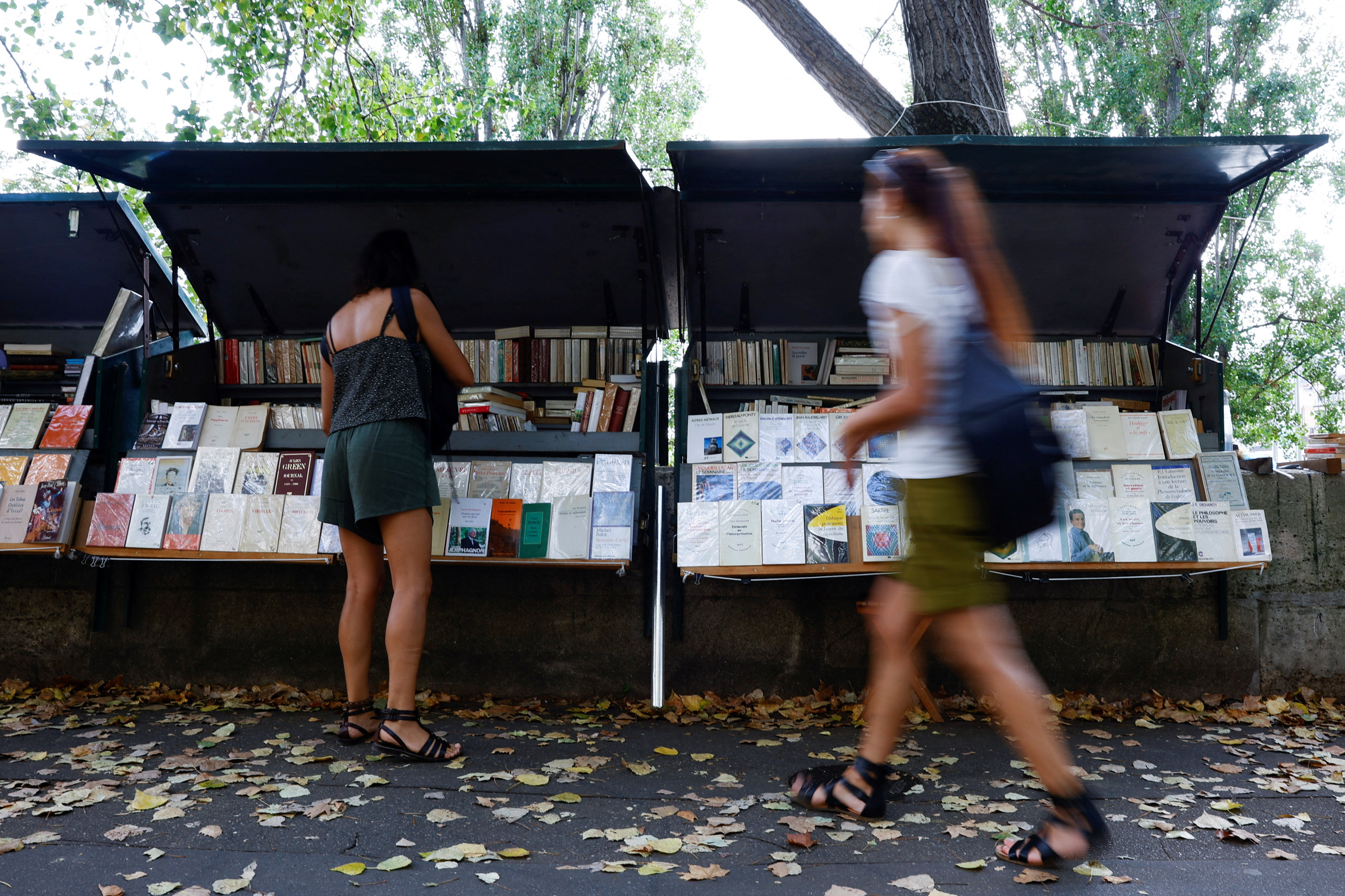 People walk past traditional street booksellers or bouquinistes along the banks of the River Seine in Paris