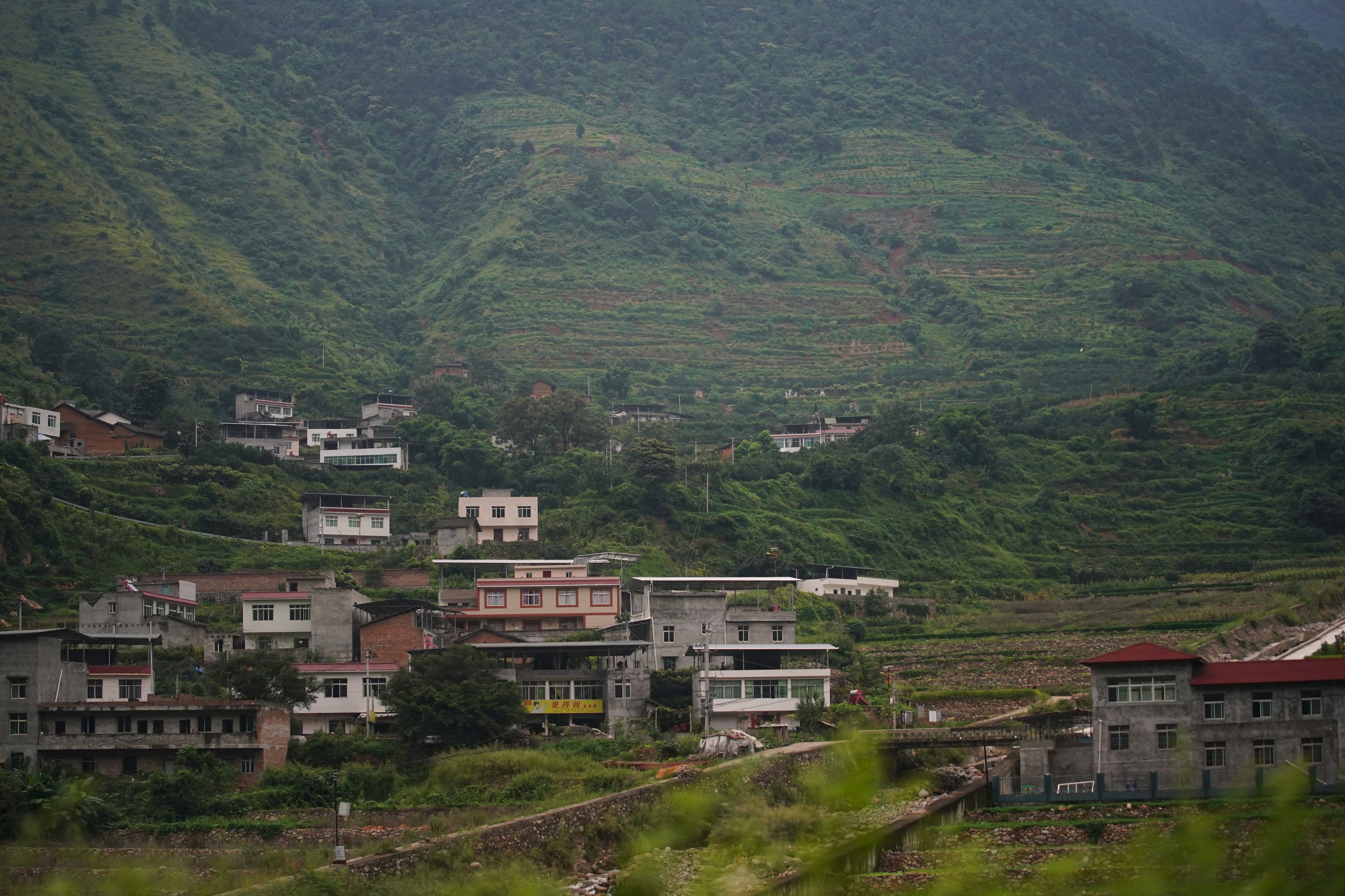Houses are seen at the foot of a mountain in Sichuan