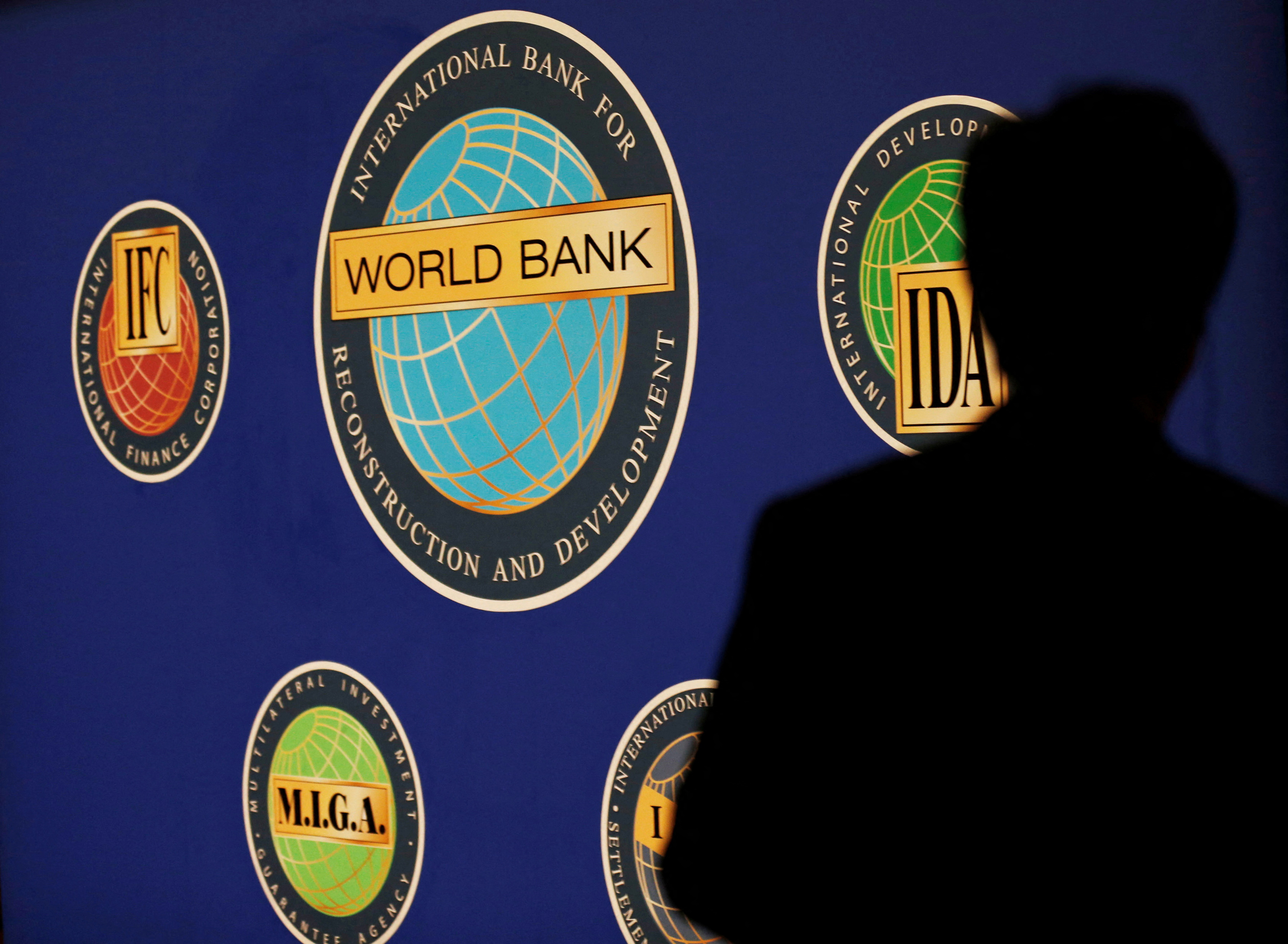 A man is silhouetted against the logo of the World Bank at the main venue for the IMF and World Bank annual meeting in Tokyo