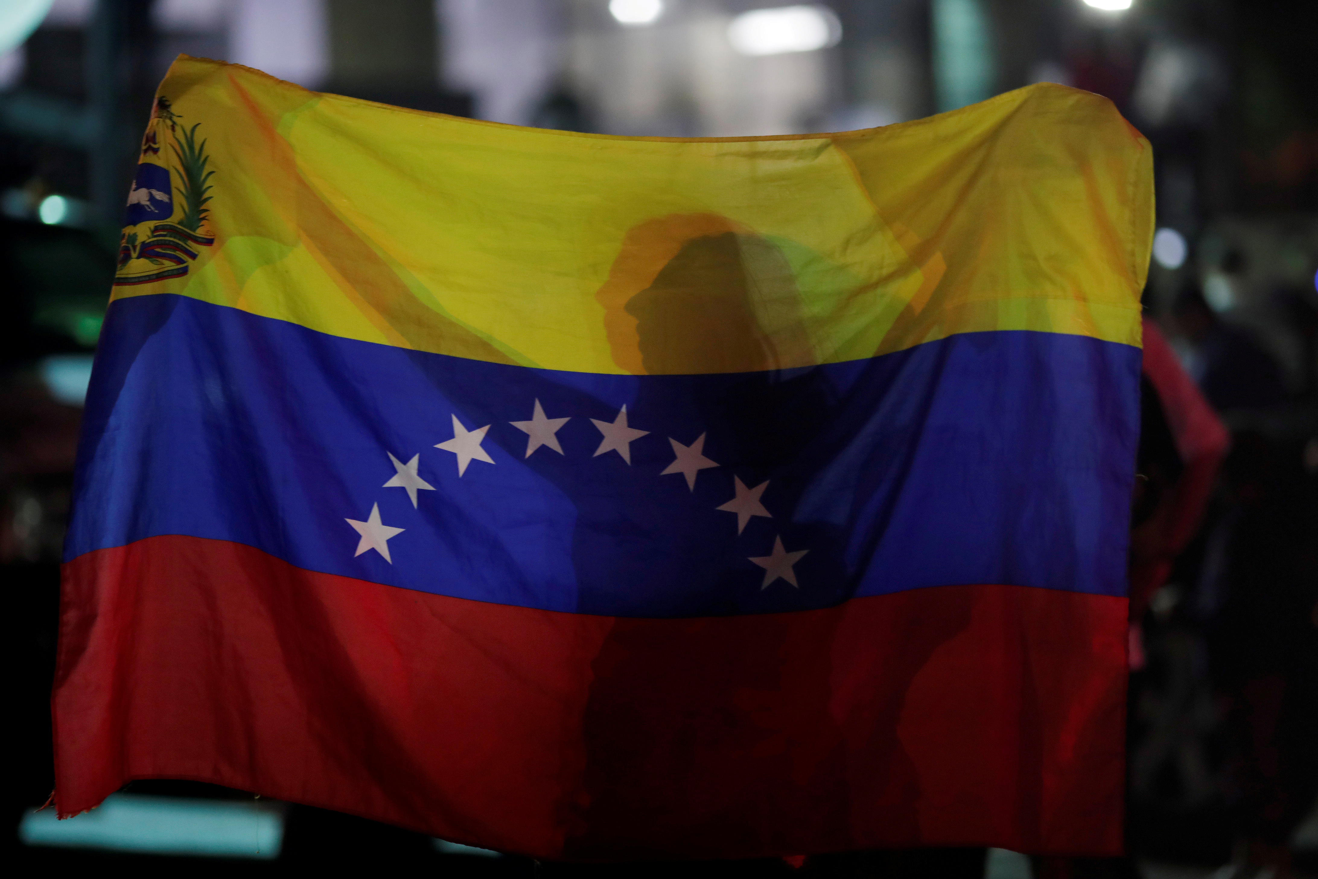 A woman holds a Venezuelan flag while participating in a candlelight vigil held for victims of recent violence in Caracas, Venezuela May 5, 2019. REUTERS/Ueslei Marcelino