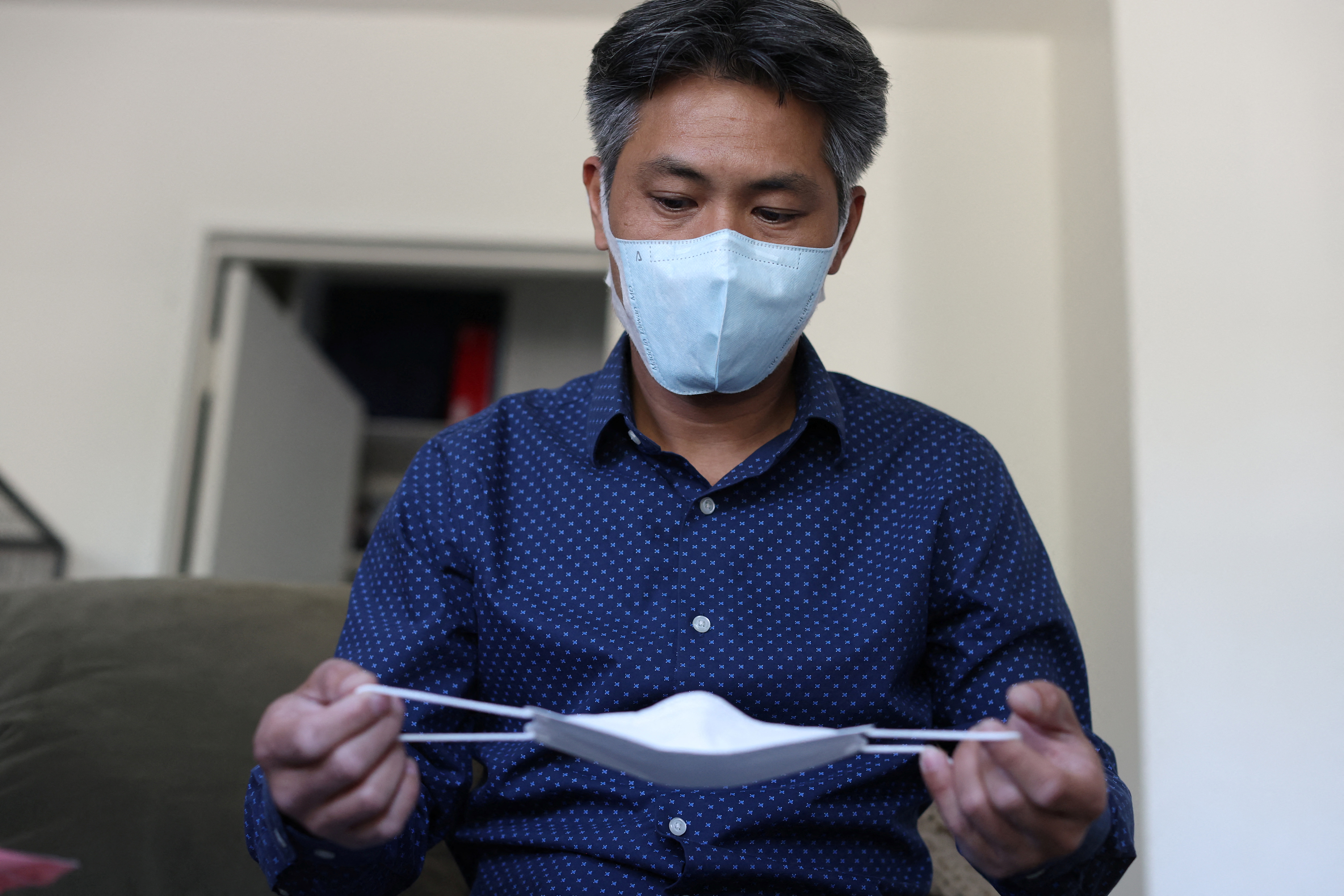 LA-based freight forwarder Tony Chen checks a kid-sized KF94 mask made in South Korea in his living room in South Pasadena