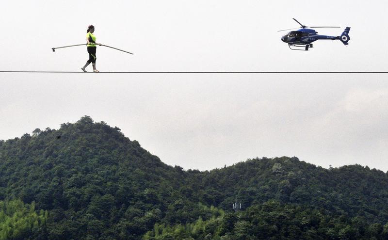 A contestant walks on tightrope as a helicopter flies past during a tightrope competition in Zhuzhou