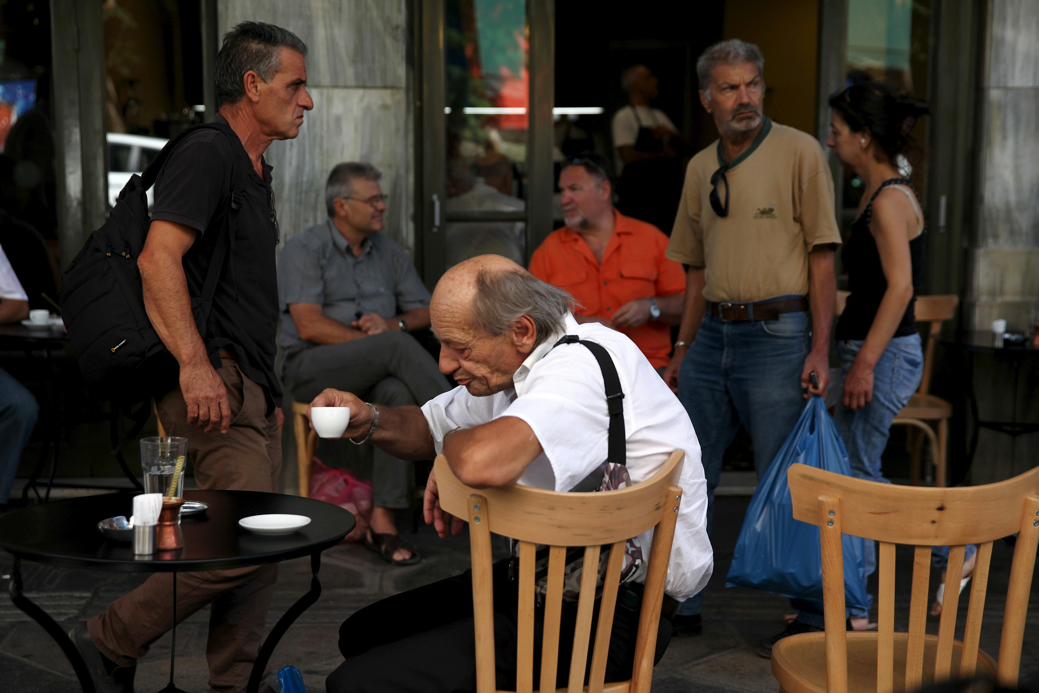 People sit outside a coffee shop in central Athens