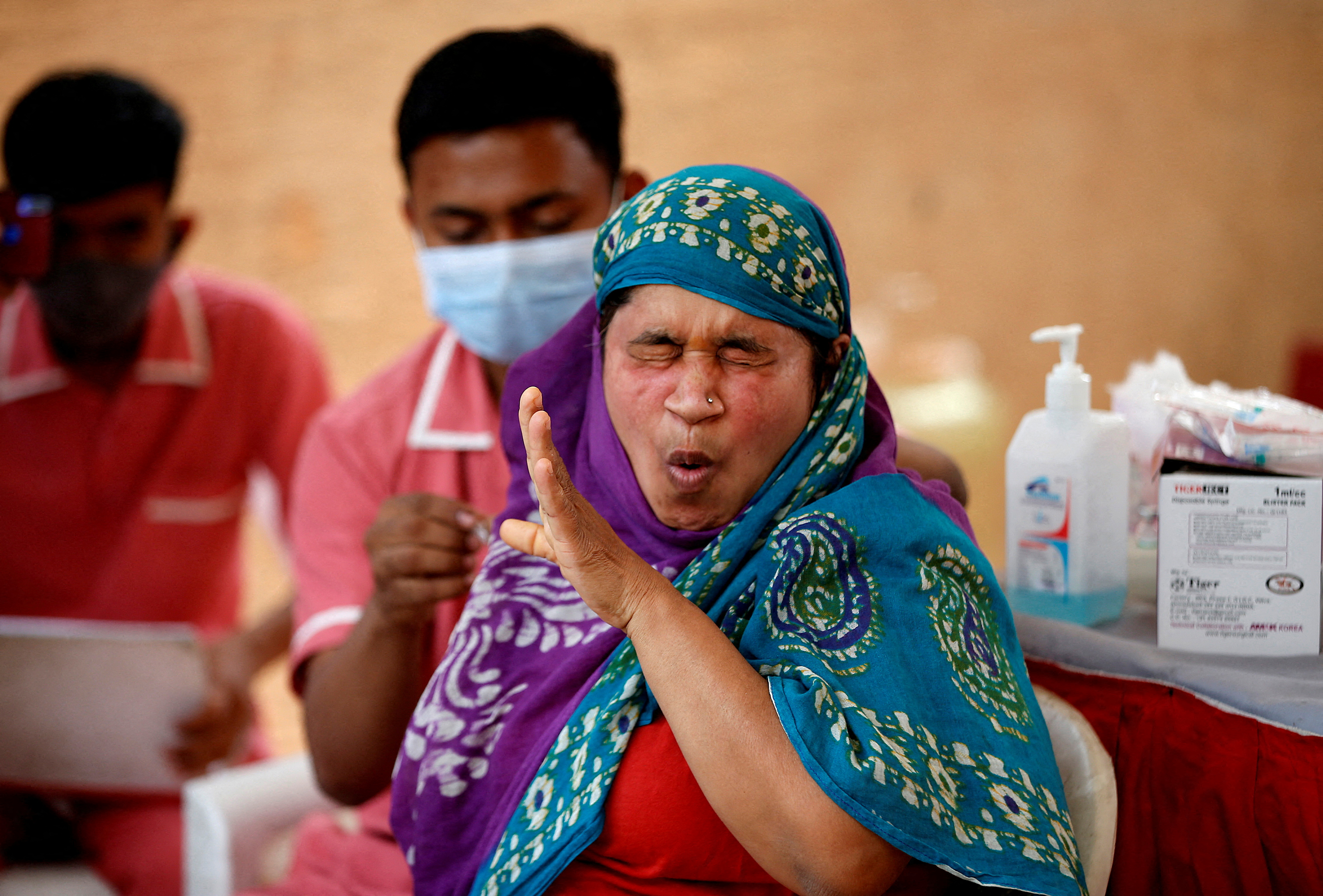 A woman reacts as she receives a dose of the COVISHIELD vaccine against the coronavirus disease (COVID-19) in Ahmedabad