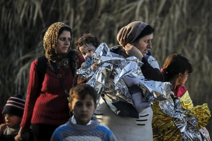 A Syrian refugee carries her child in a thermal blanket as refugees and migrants arrive on an overcrowded boat on the Greek island of Lesbos
