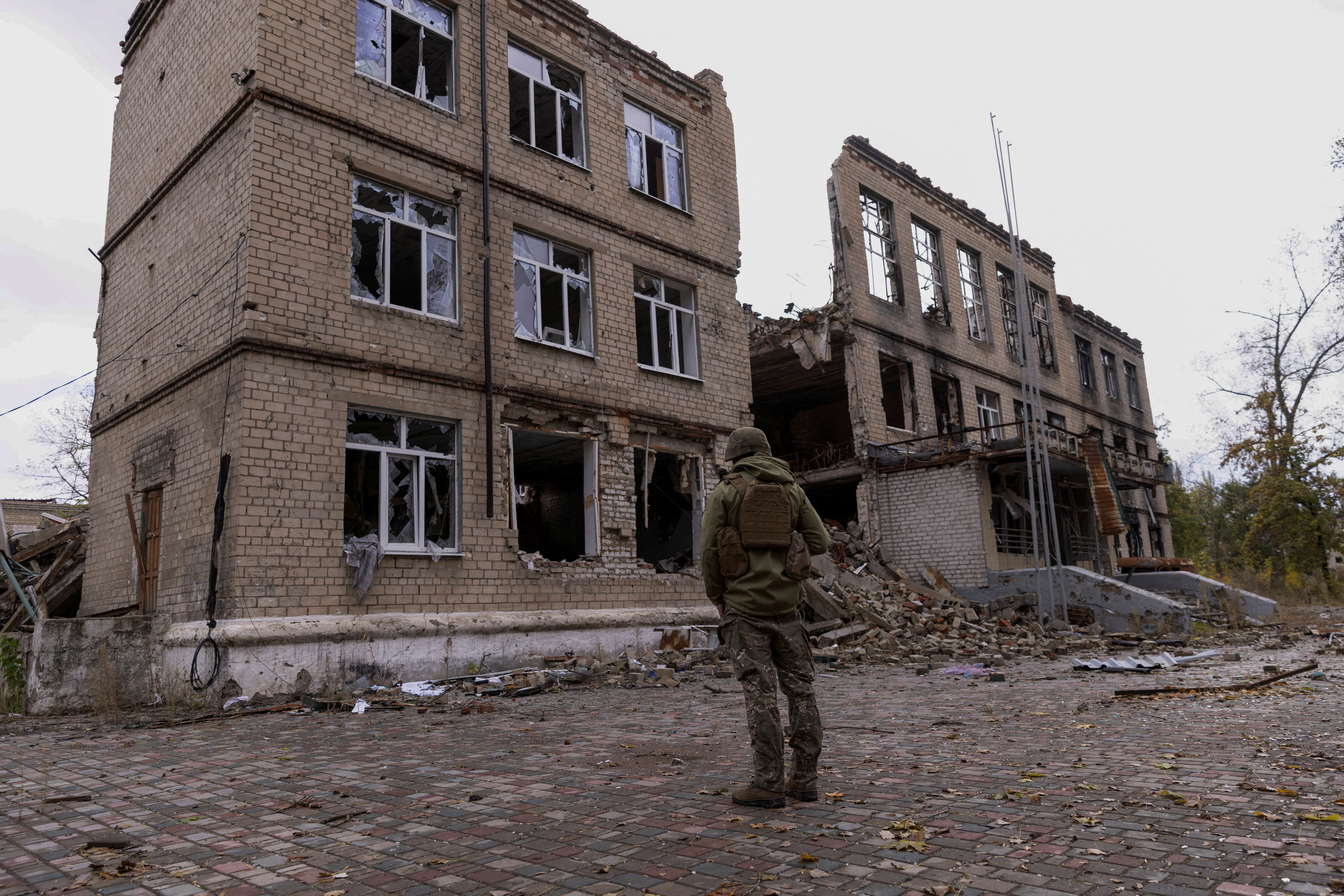 A police officer stands in front of a damaged building in Avdiivka