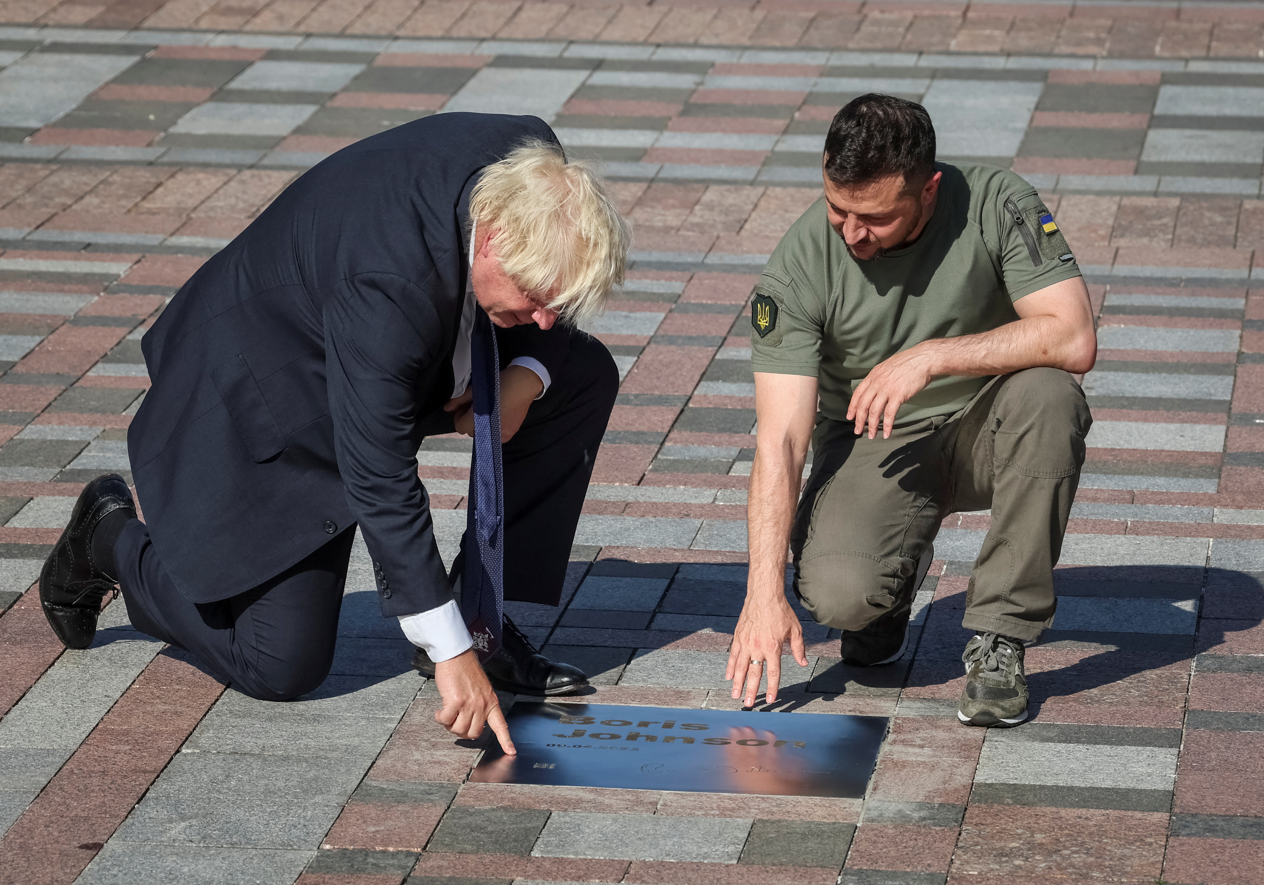 Ukraine's President Zelenskiy and British Prime Minister Johnson open a plate with his name on the Alley of Bravery in Kyiv