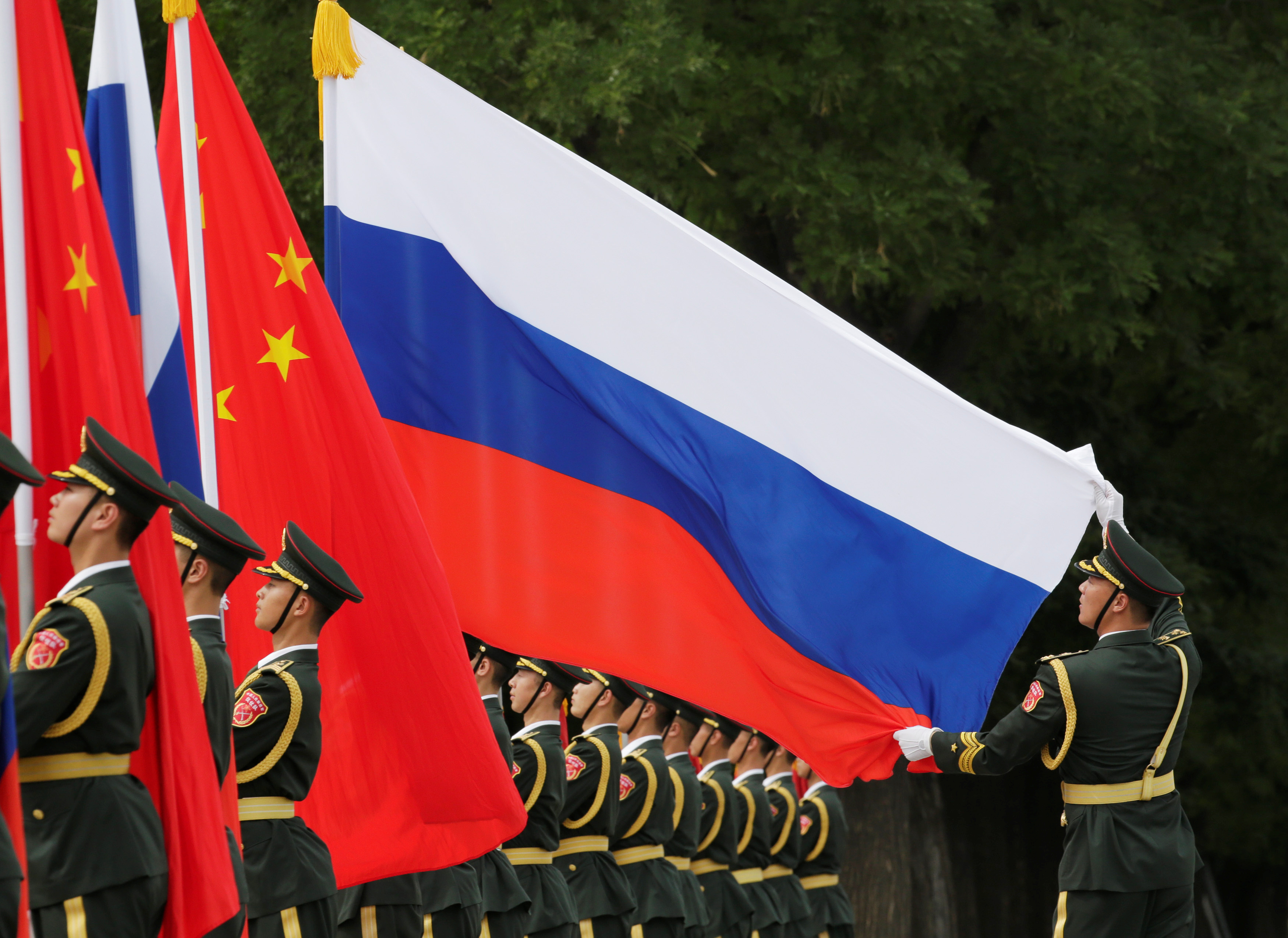 A military officer adjusts a Russian flag ahead of a welcome ceremony in Beijing