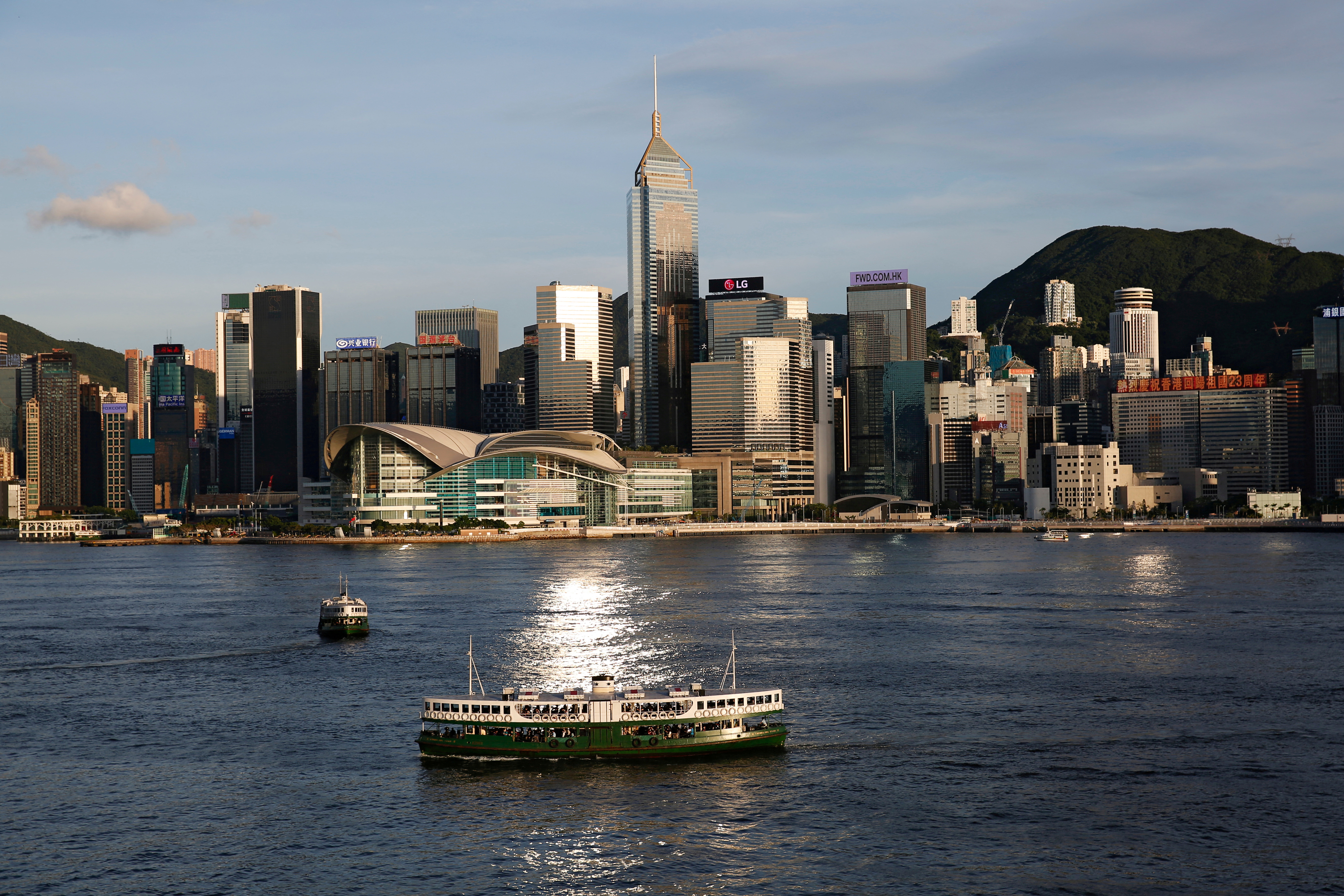 A Star Ferry boat crosses Victoria Harbour in front of a skyline of buildings in Hong Kong