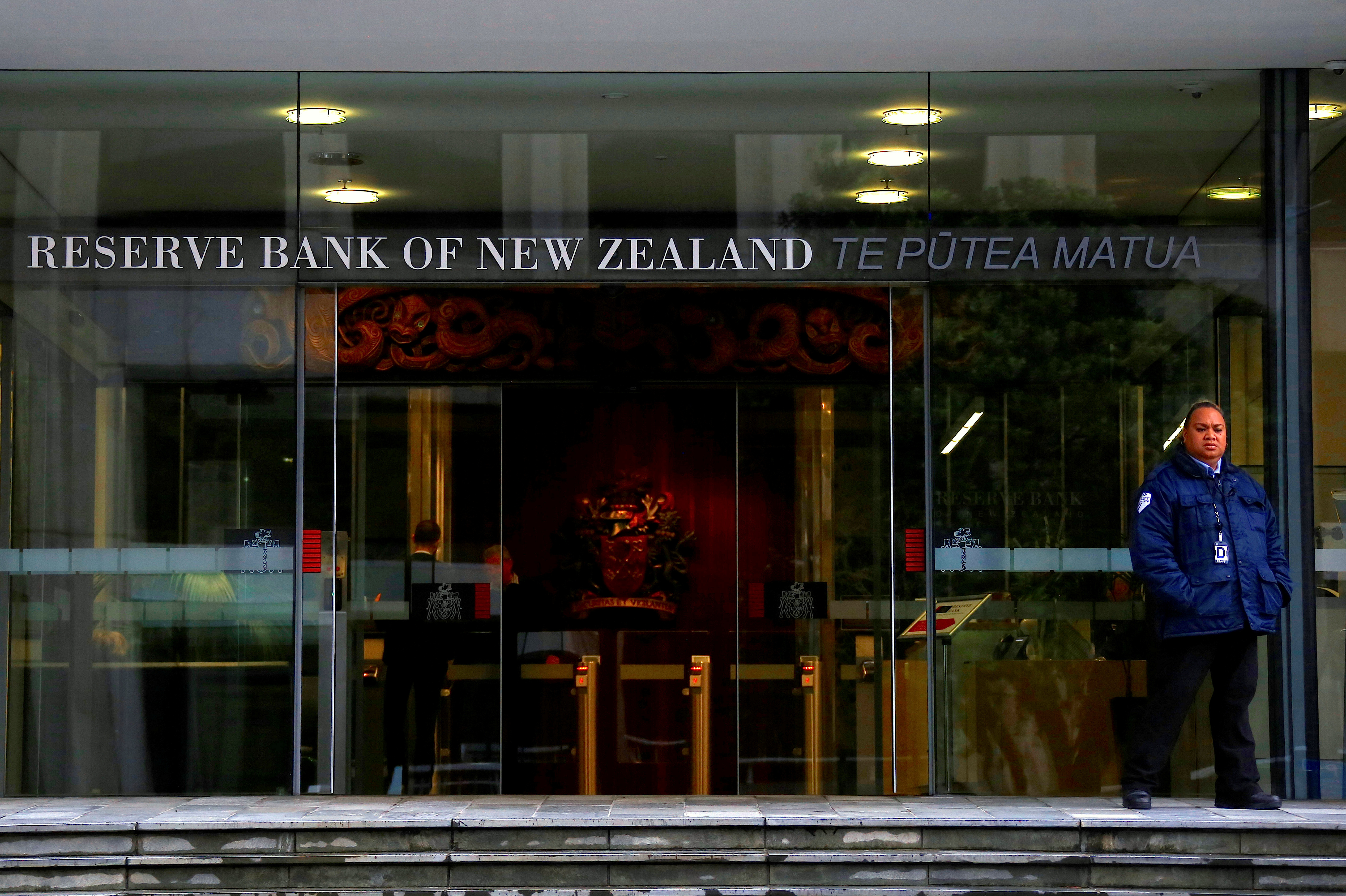 A security guard stands outside the main entrance to the Reserve Bank of New Zealand located in central Wellington, New Zealand