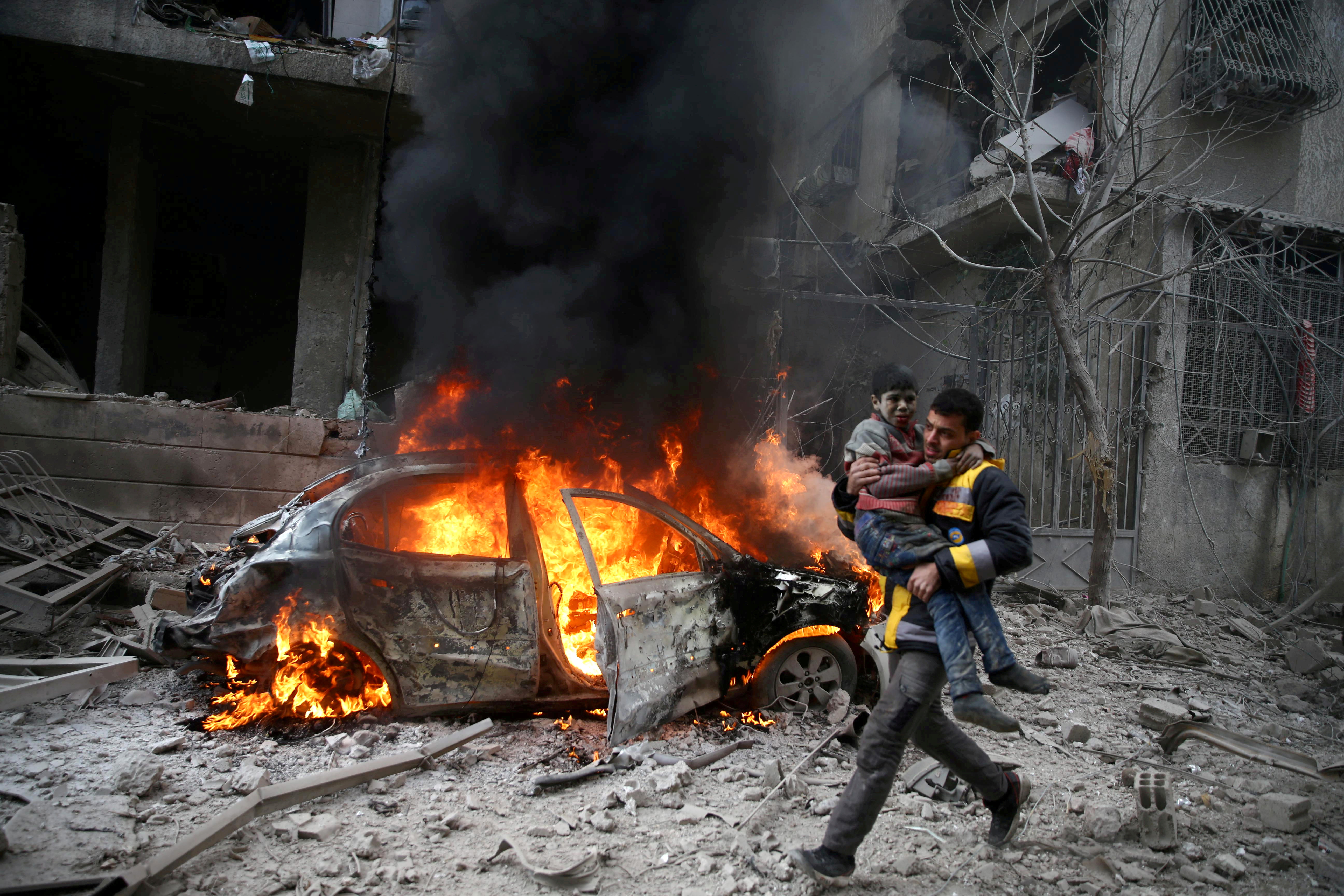 A Syrian Civil Defence member carries a wounded child in Hamoria, Eastern Ghouta, Damascus