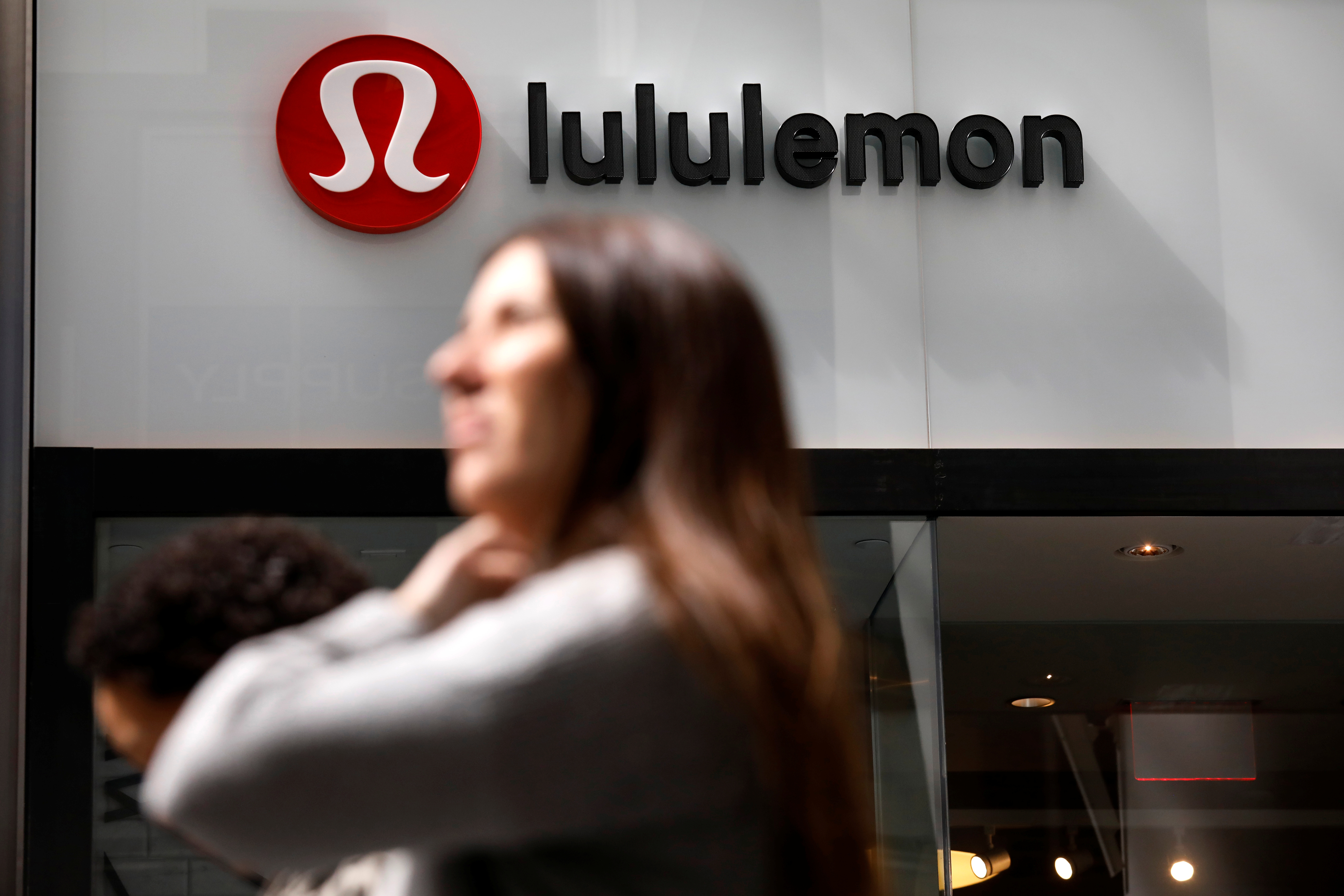 People walk past a store by yogawear retailer Lululemon Athletica in New York